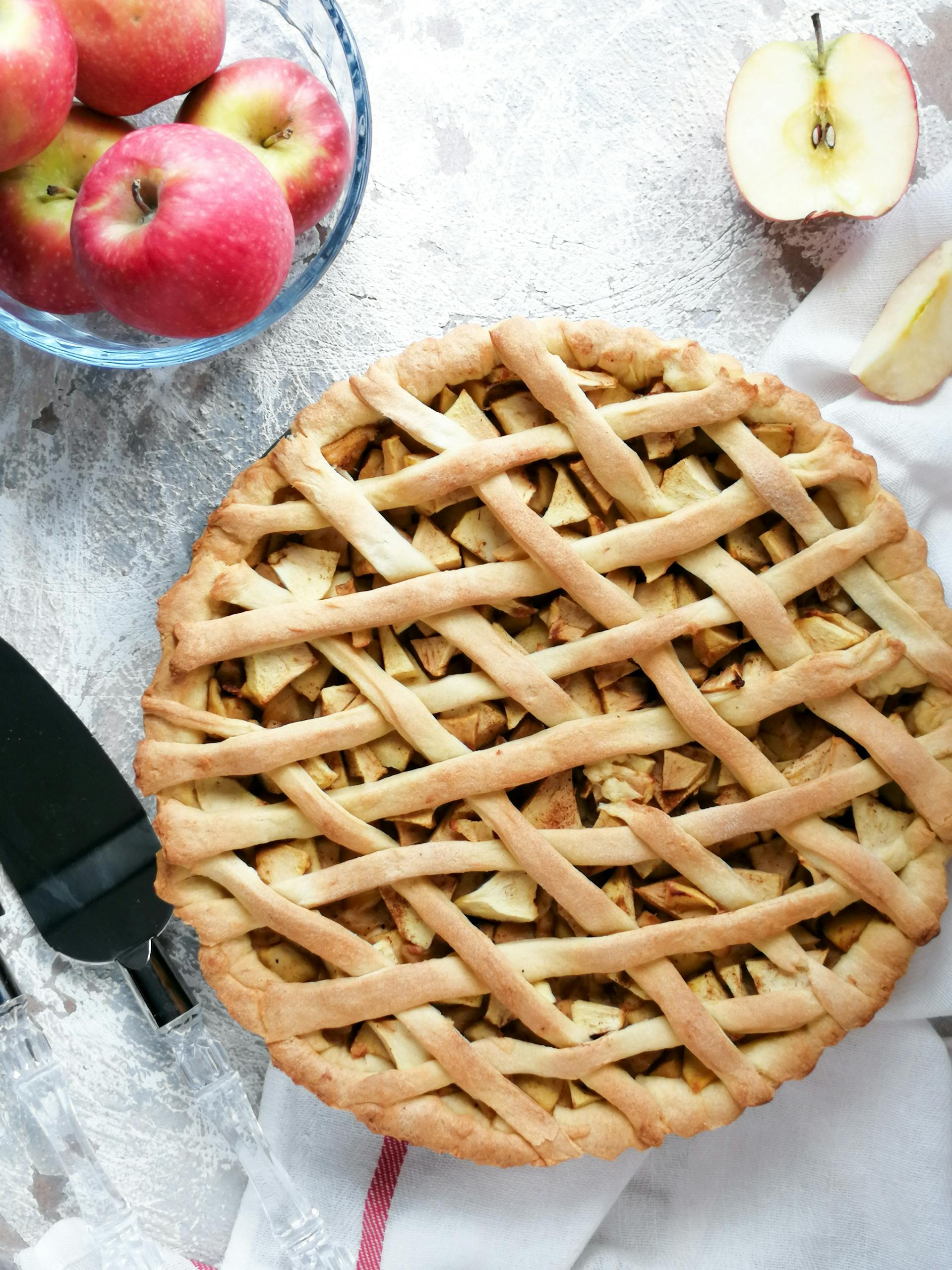 Une tarte aux pommes posée sur une table avec un bol de pommes | Source : Pexels