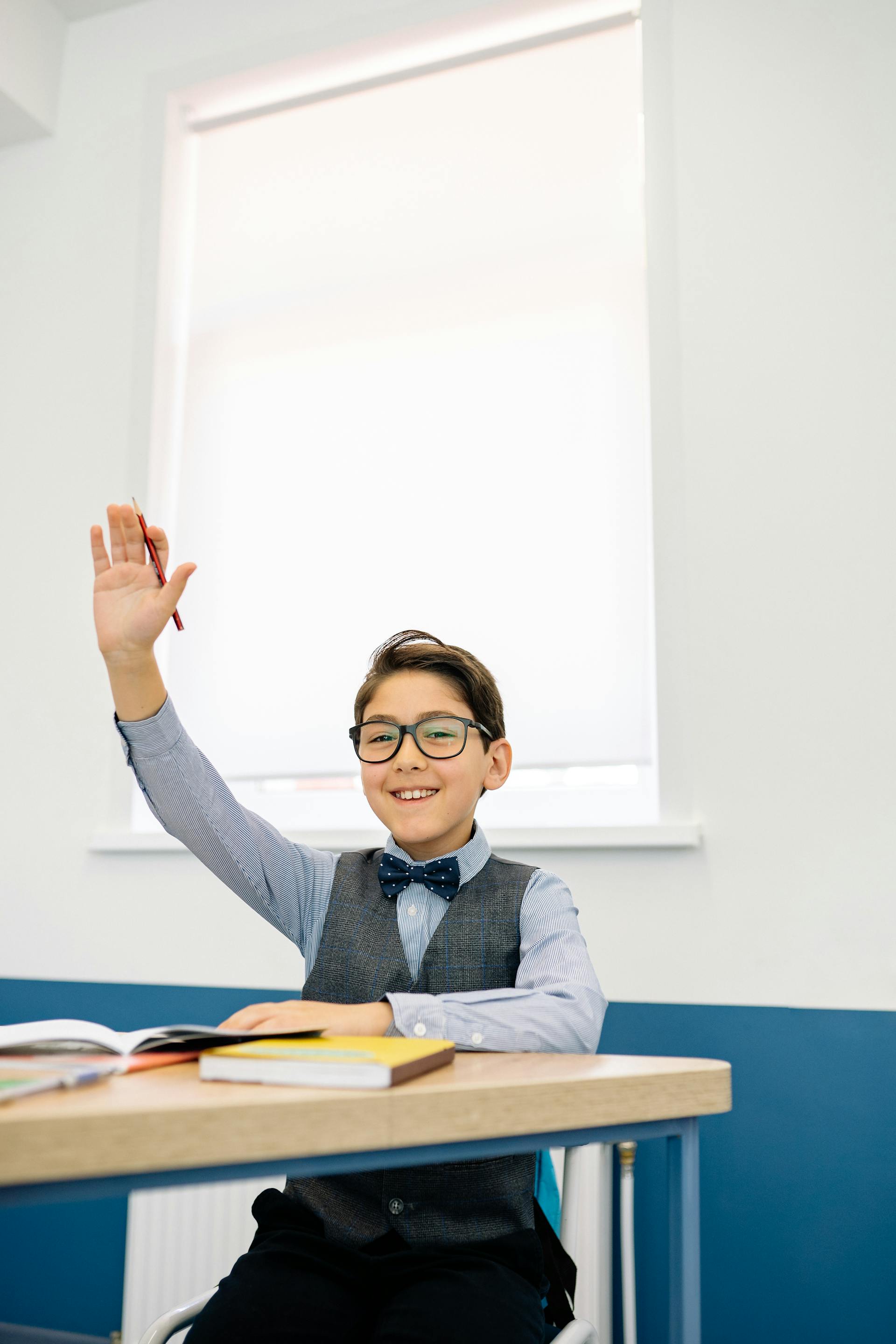 Un jeune garçon qui lève la main dans une salle de classe | Source : Pexels