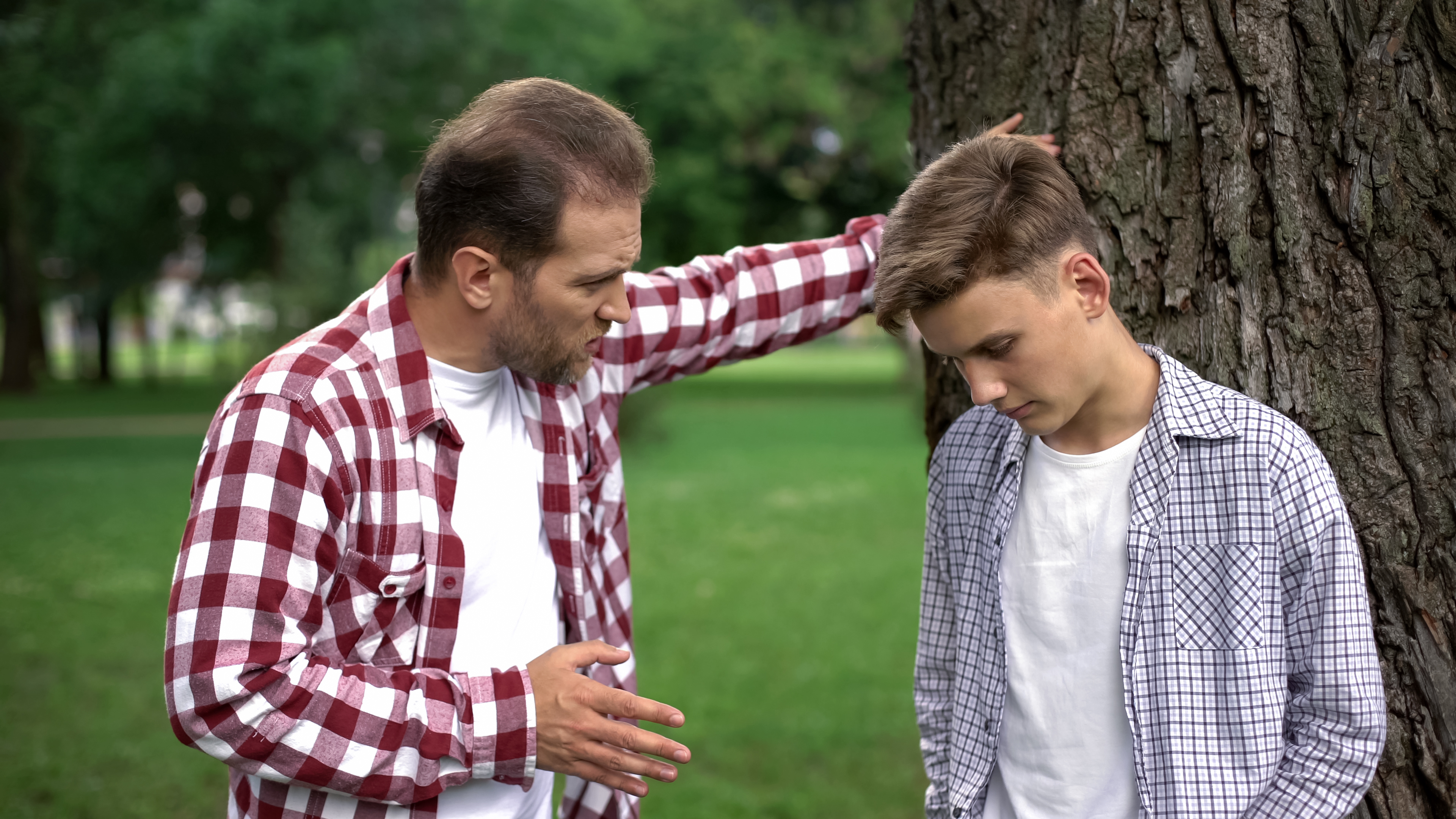 Un père sévère réprimande son fils pour ses mauvais résultats scolaires. | Source : Shutterstock