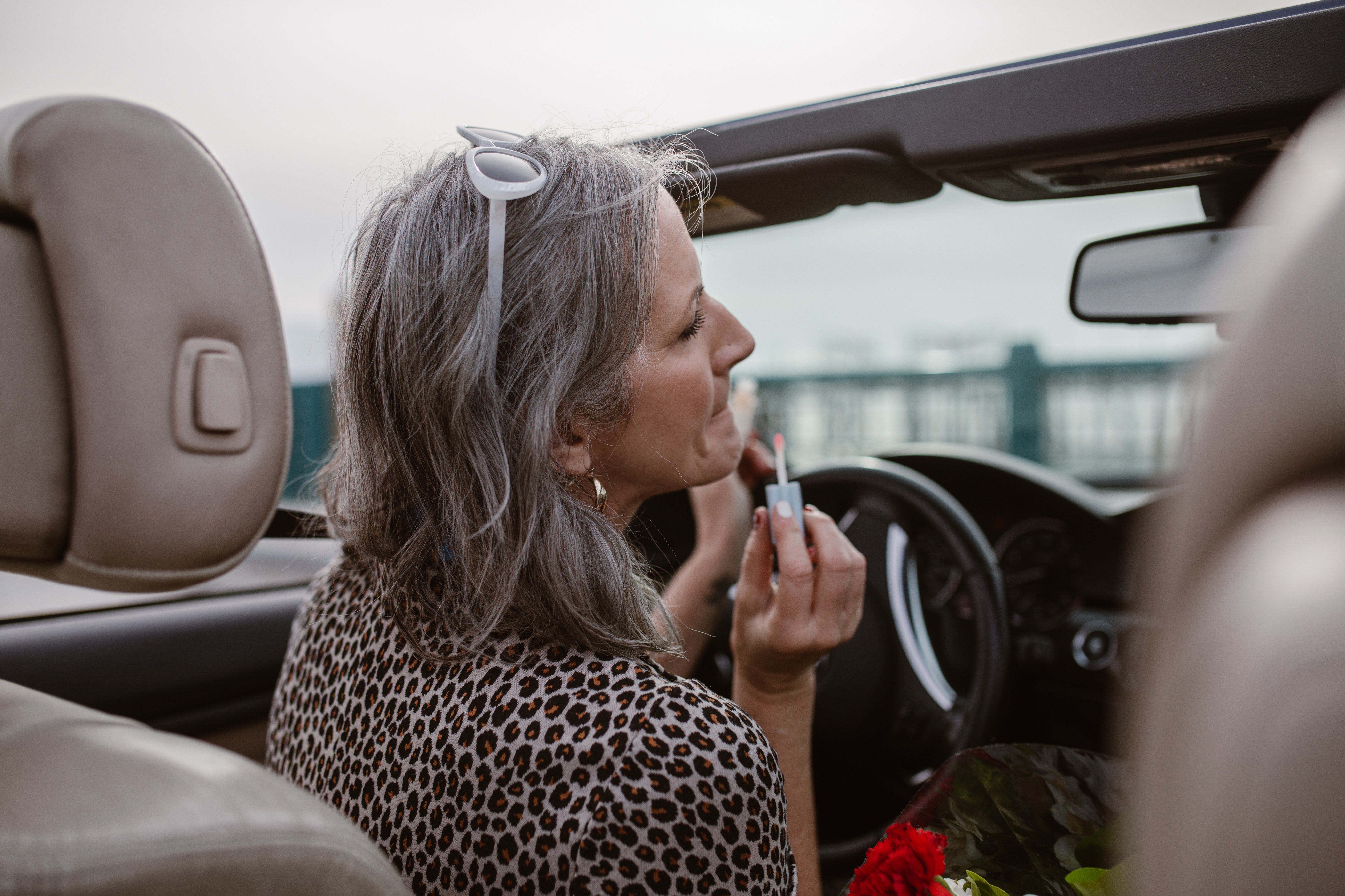 Une femme s'appliquant du gloss dans une voiture flambant neuve | Source : Pexels