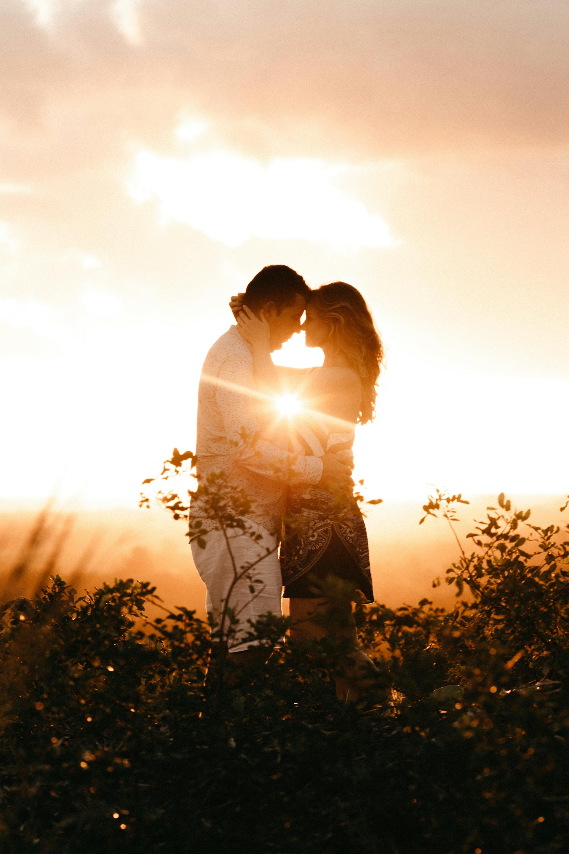 Un couple qui s'enlace dans un champ à l'heure dorée | Source : Pexels