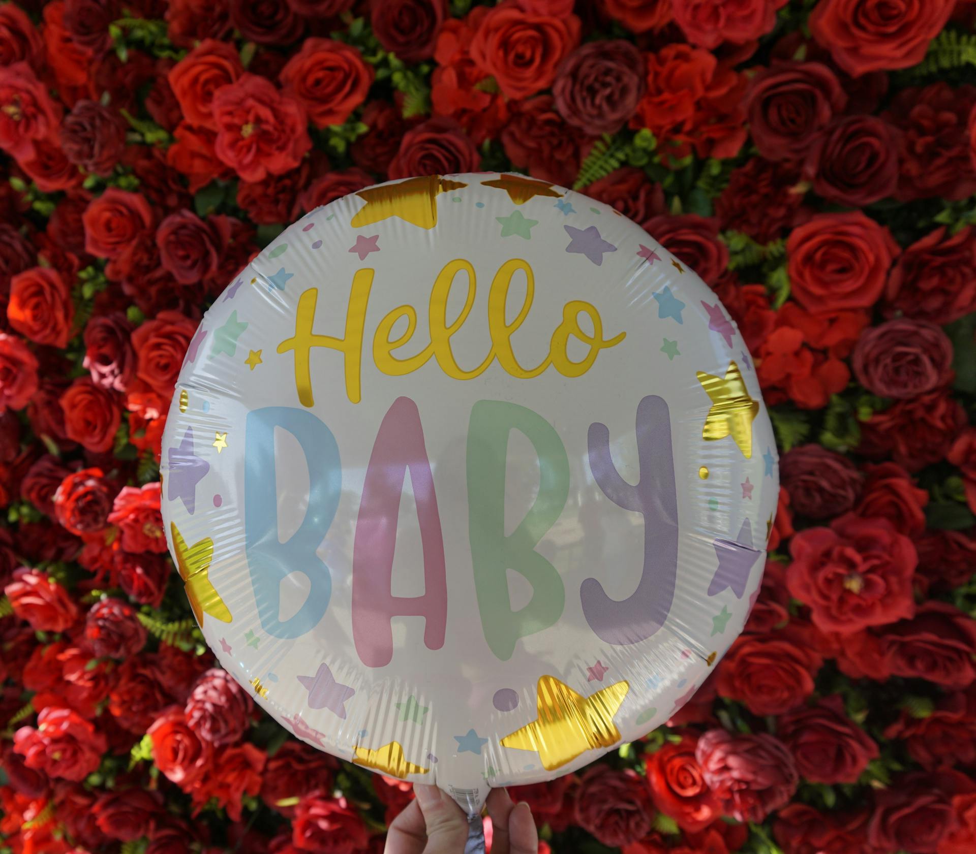 Une personne tenant un ballon avec des roses rouges en arrière-plan | Source : Pexels