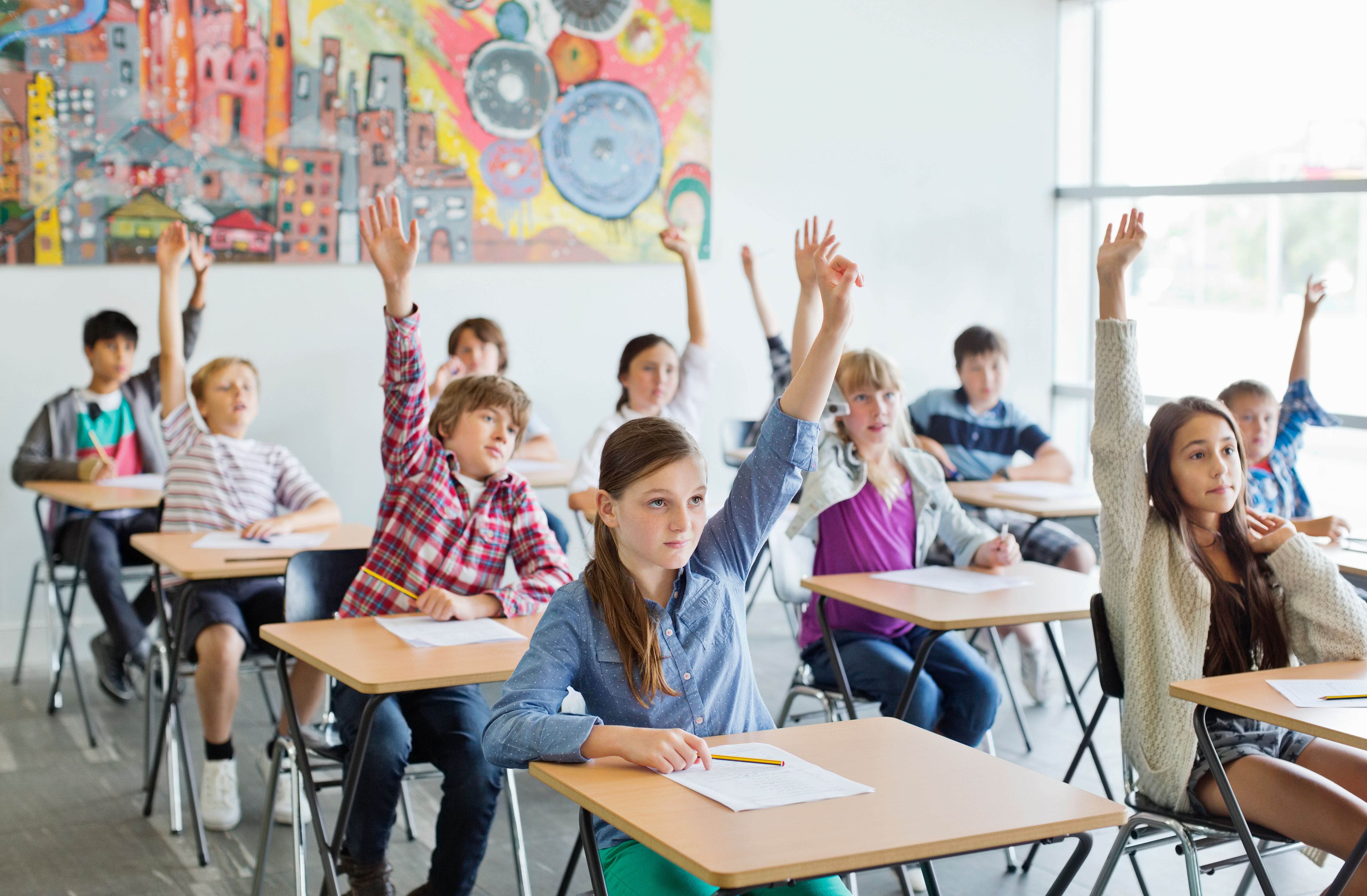Des élèves lèvent la main en classe. | Source : Getty Images