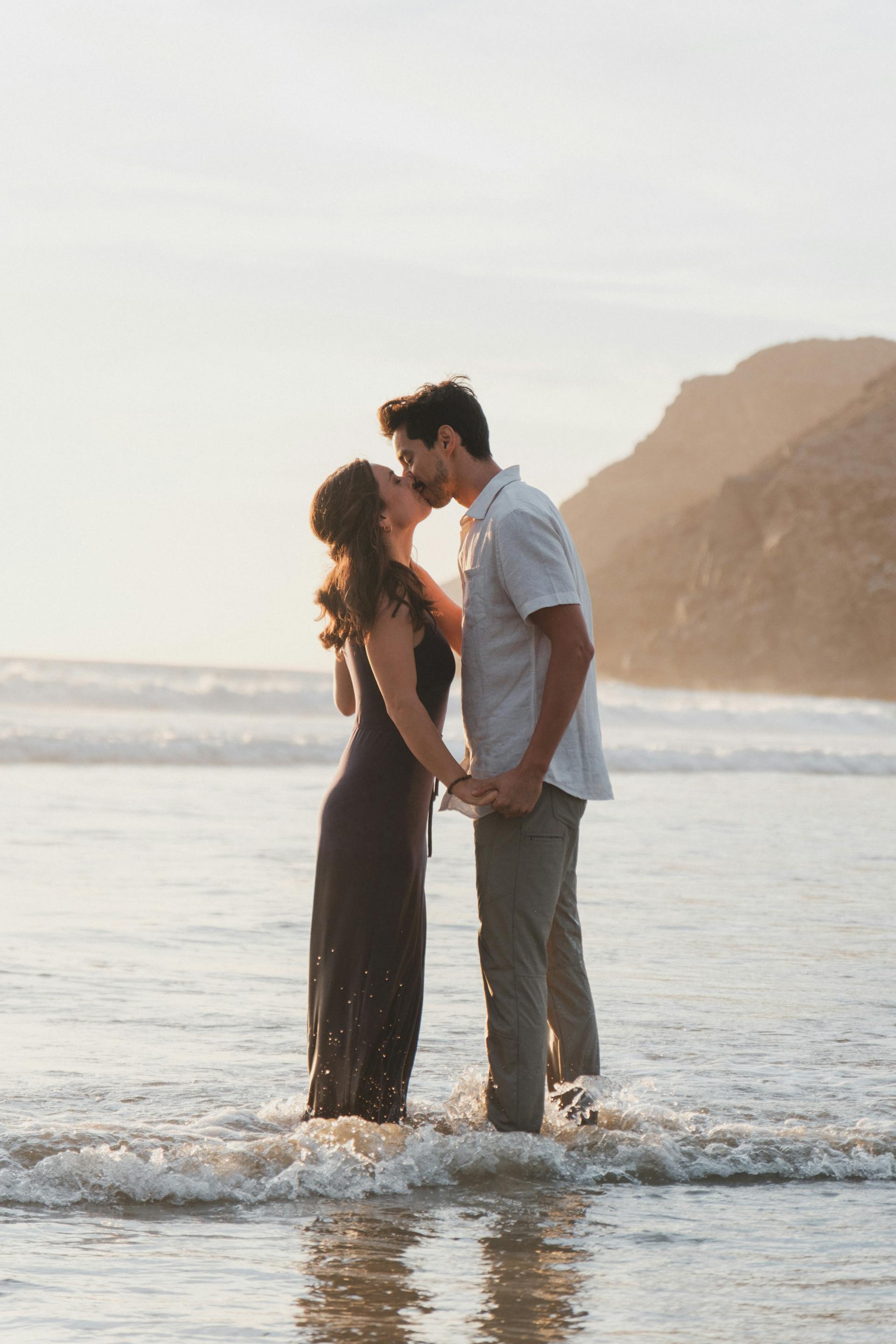Un couple s'embrasse alors qu'il a les chevilles dans la mer | Source : Pexels