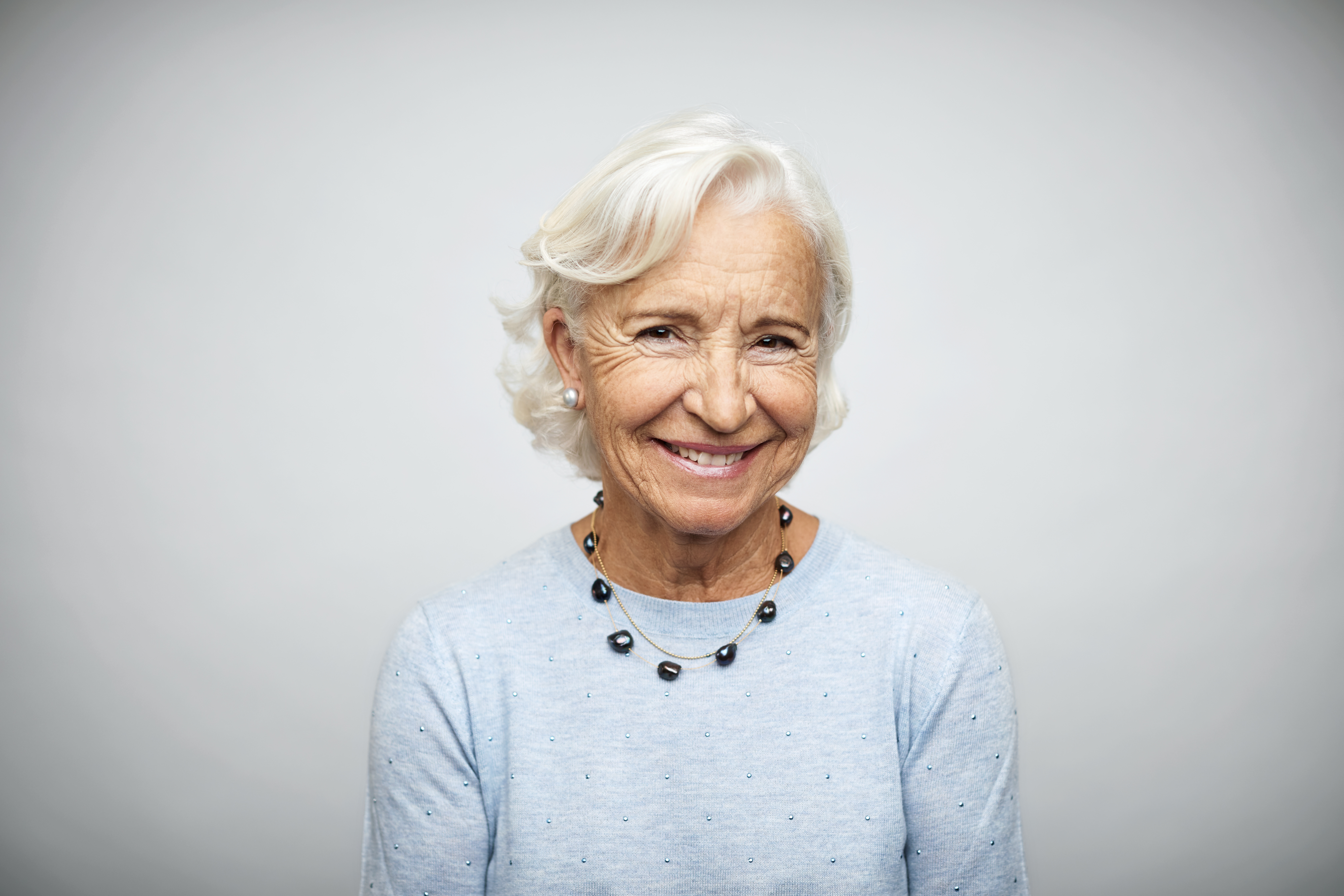 Une femme d'affaires âgée souriant sur fond blanc | Source : Getty Images