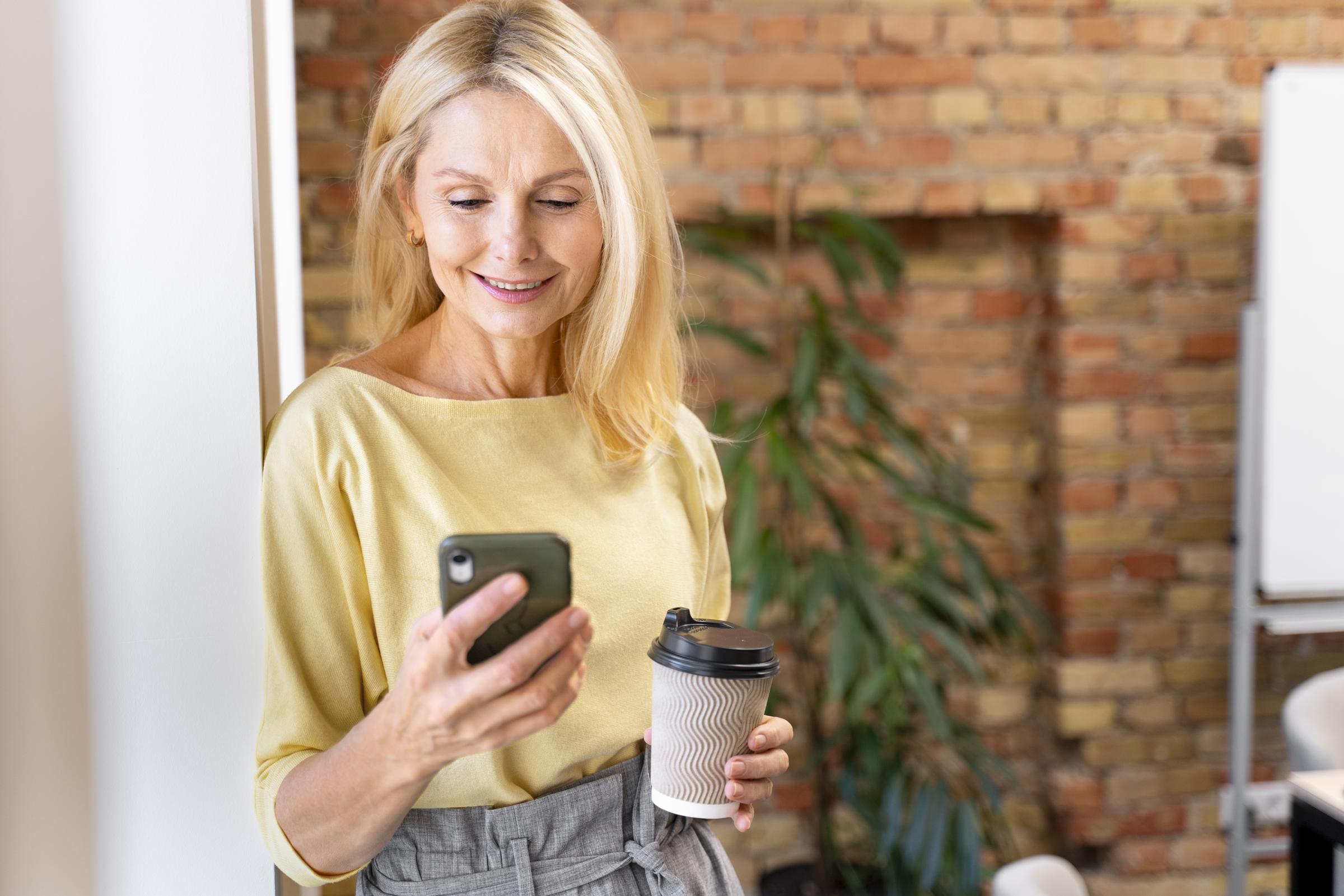 Une femme souriante sur son téléphone | Source : Freepik