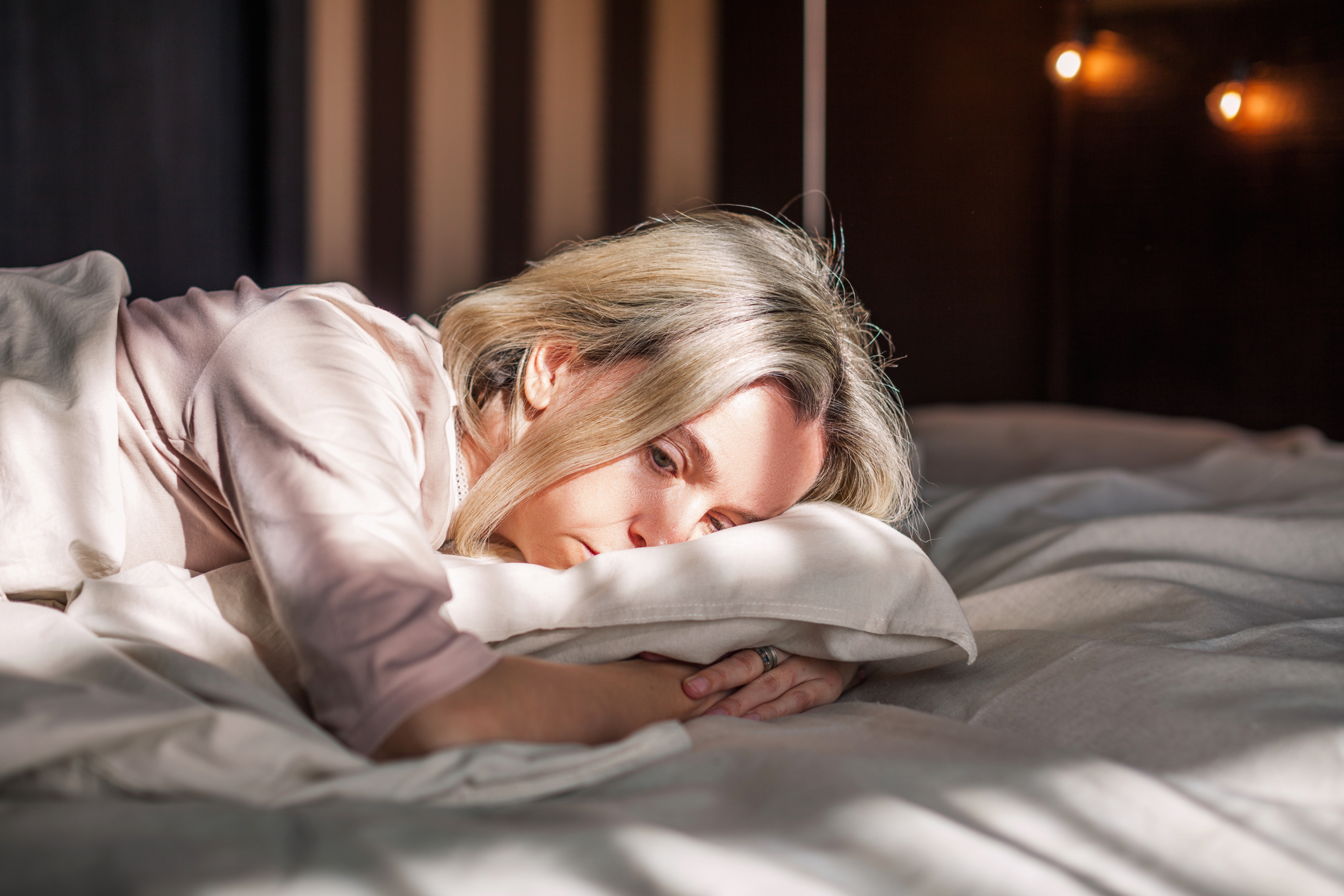 Une femme déprimée a du mal à s'endormir et reste allongée dans son lit, bien éveillée : Shutterstock
