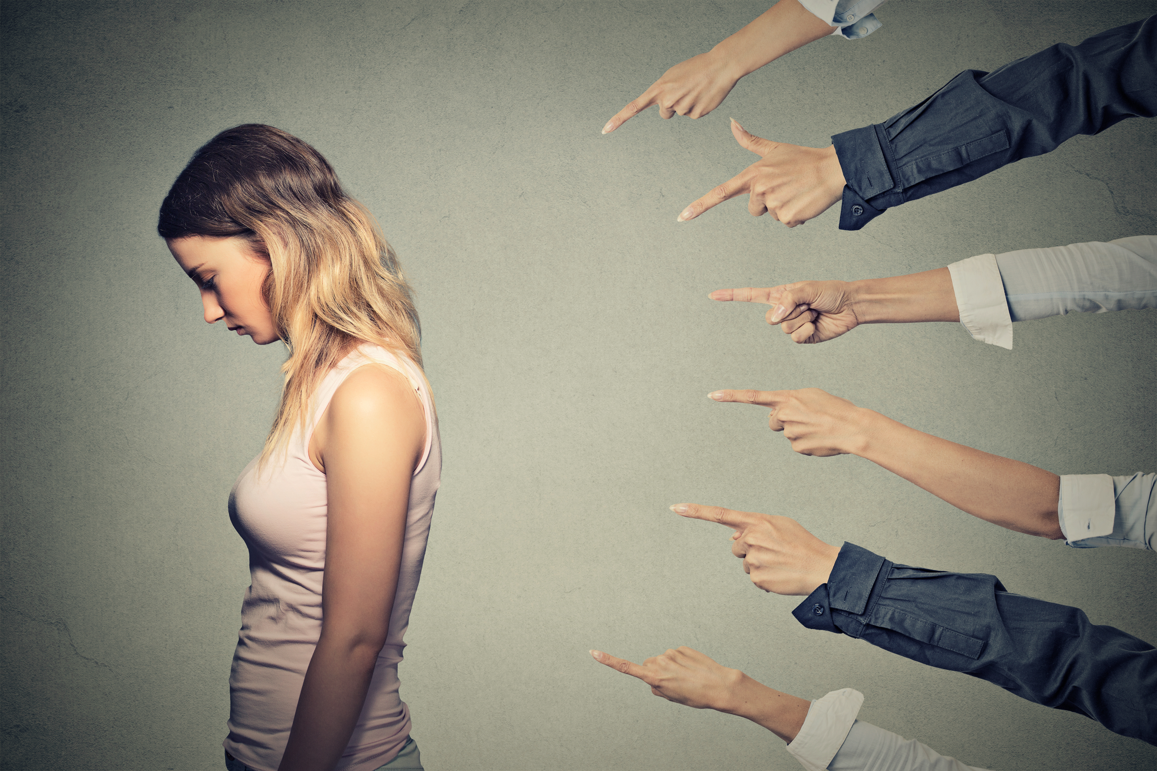 Femme contrariée avec de nombreuses mains pointées vers elle | Source : Shutterstock