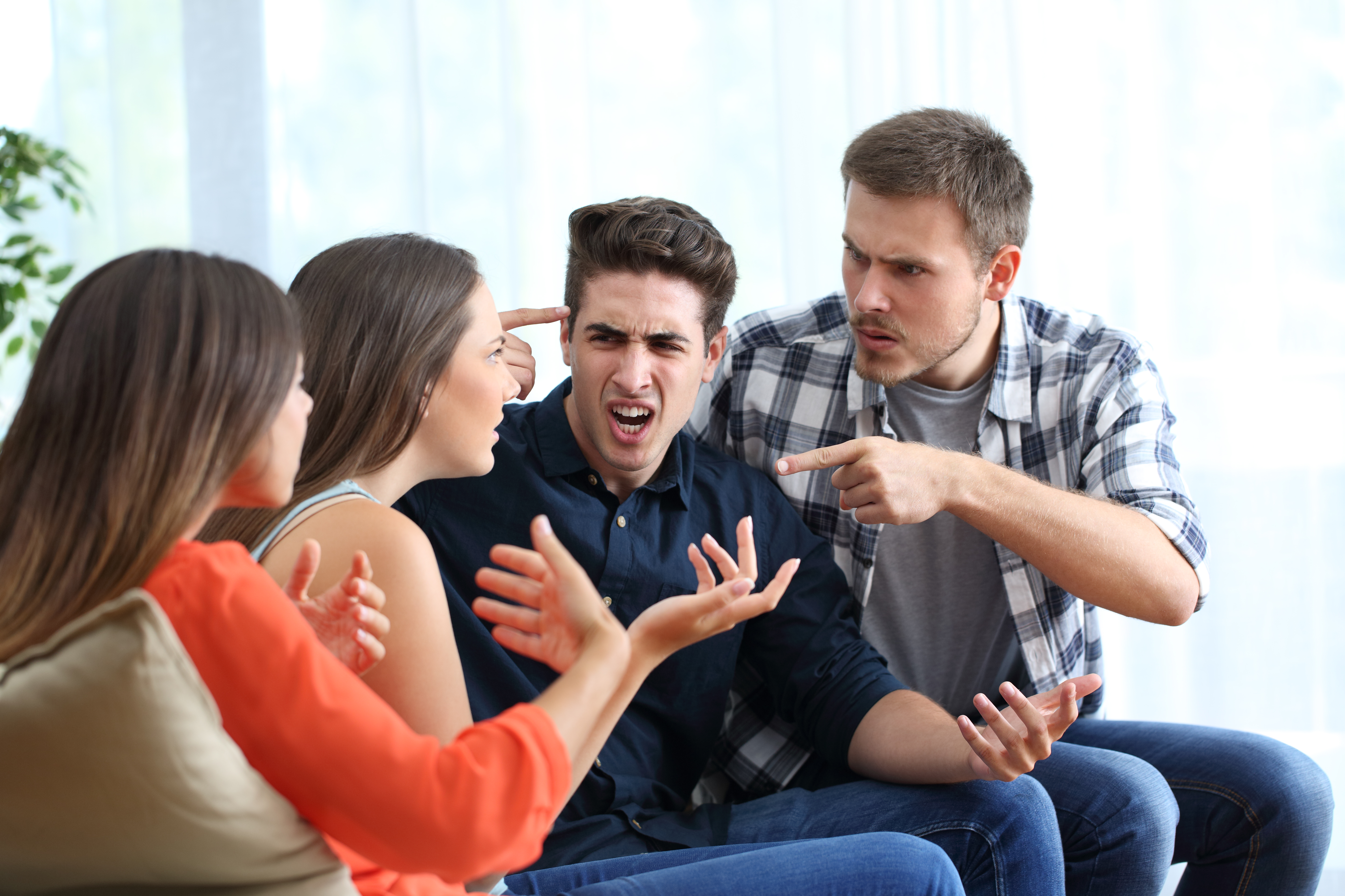 Quatre amis en colère qui se disputent à la maison | Source : Getty Images
