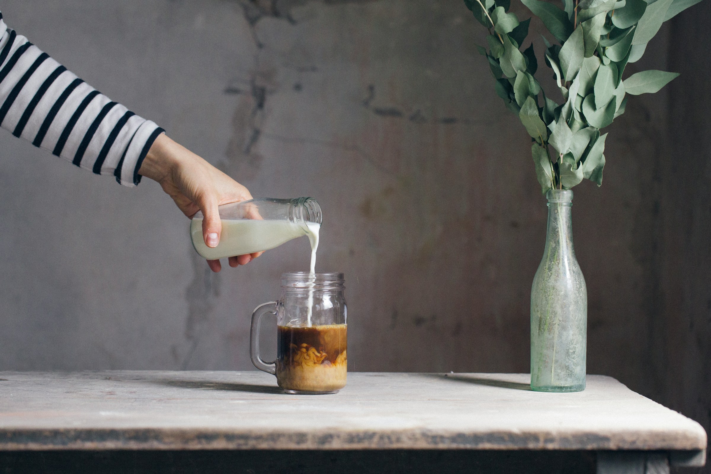 Une personne versant du lait dans du café | Source : Unsplash