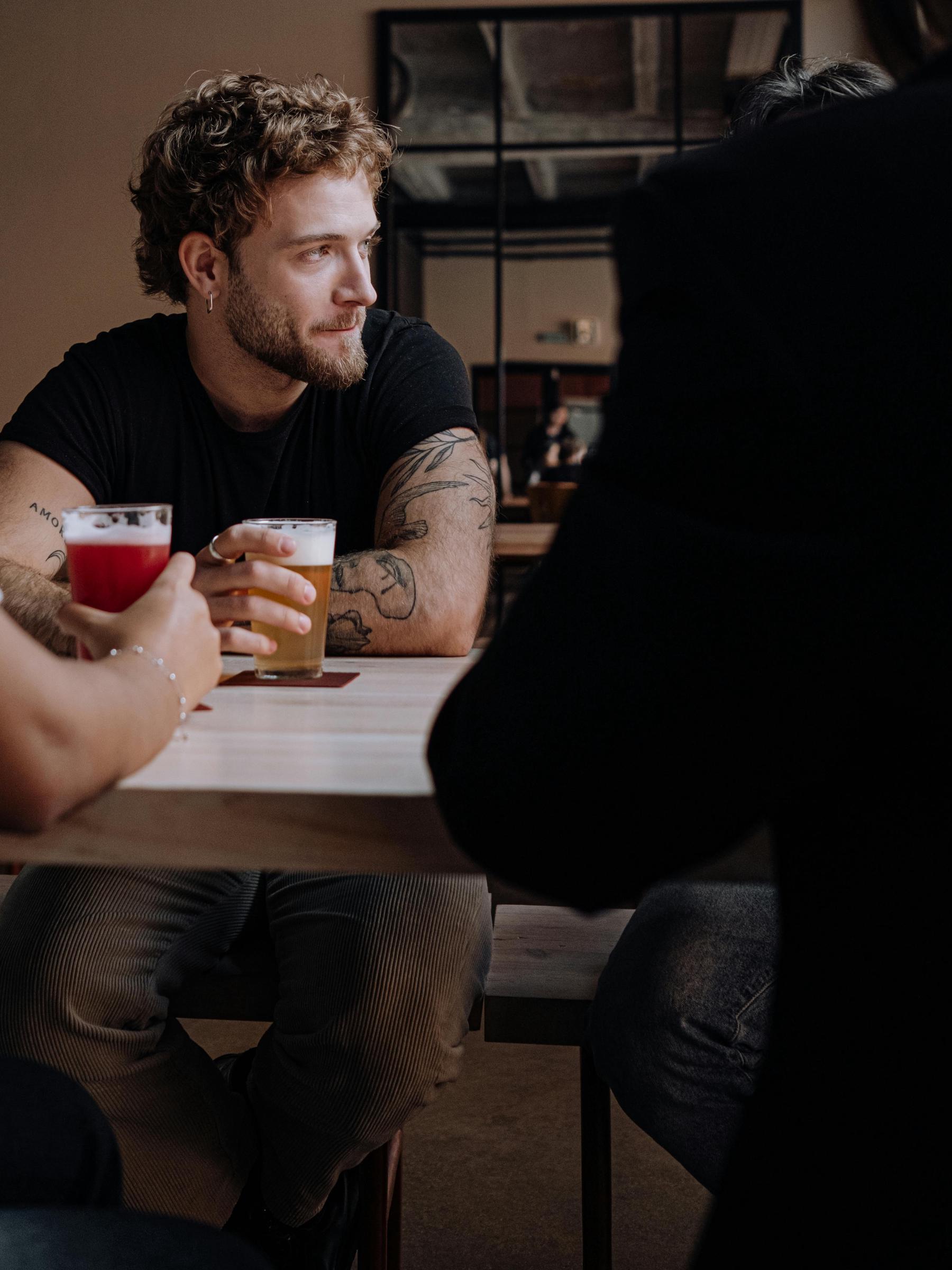 A man looking to the side, sitting with a beer in his hand | Source: Pexels