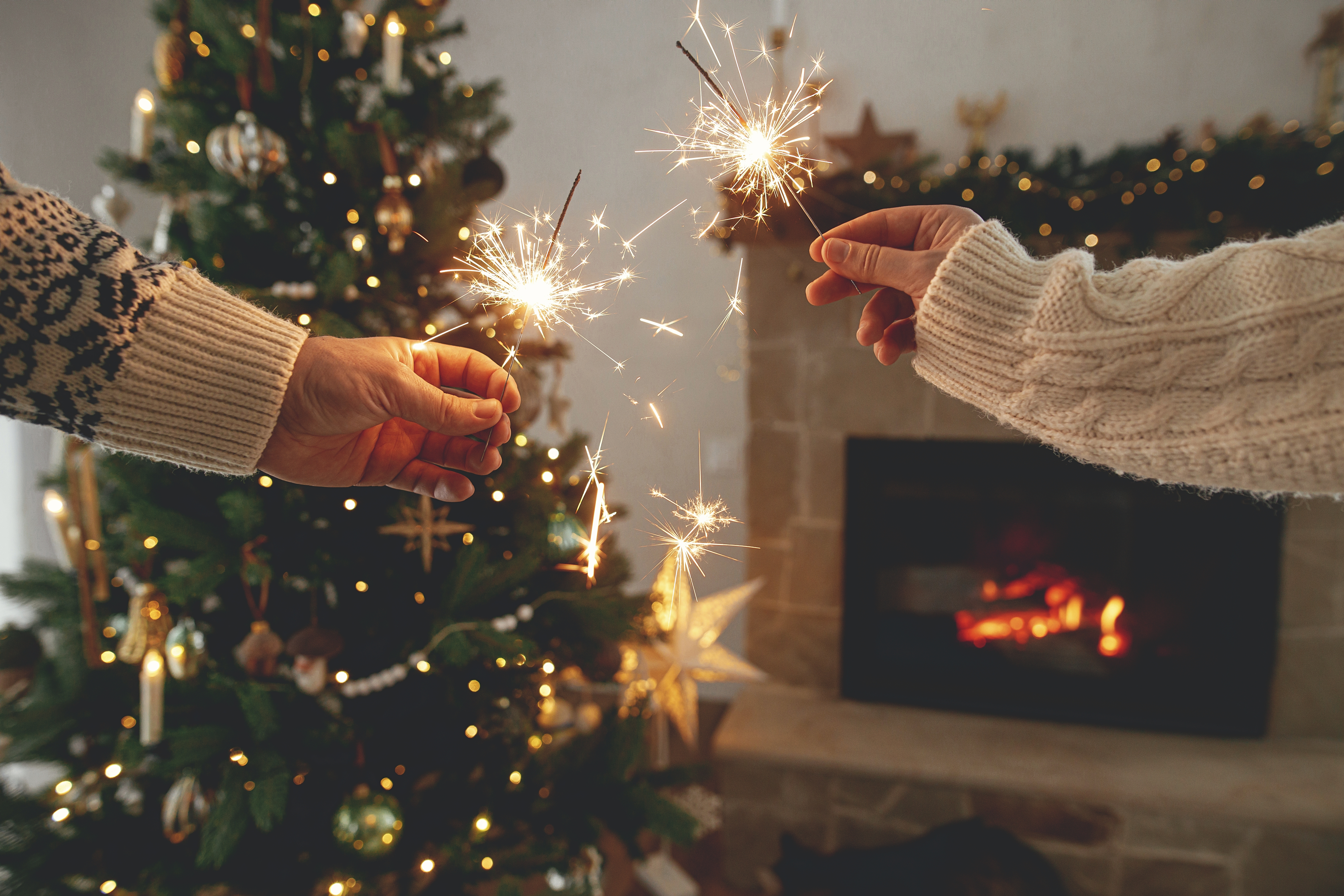 Deux personnes faisant brûler des cierges magiques près d'un arbre de Noël | Source : Shutterstock