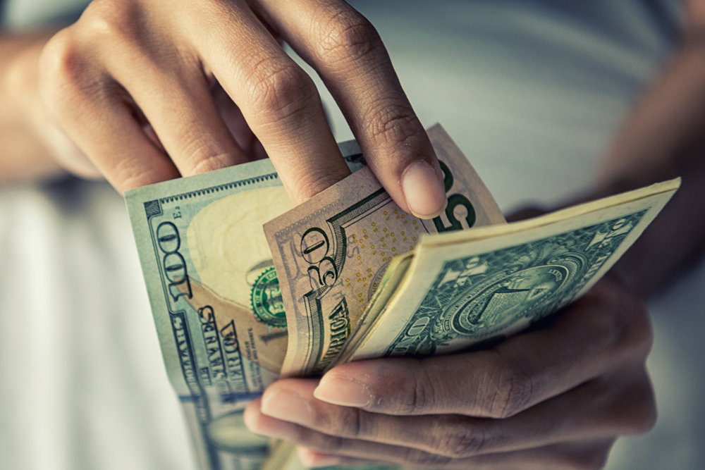 Gros plan d'une personne tenant de l'argent | Source : Shutterstock