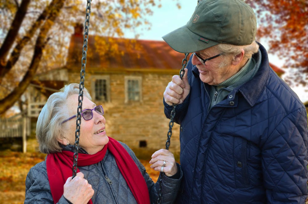 Un homme âgé se connectant avec sa femme assise sur une balançoire. | Pexels