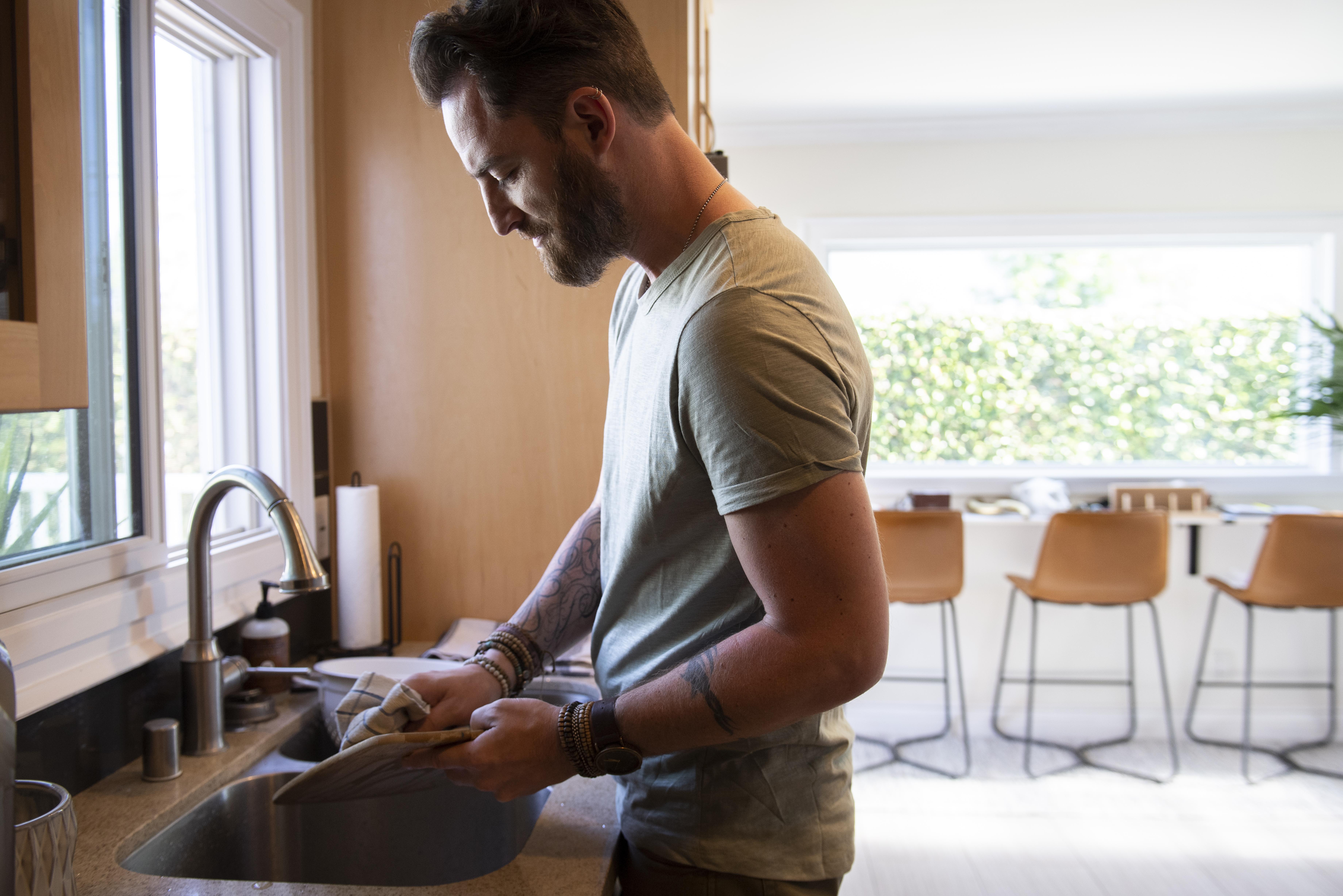 Homme faisant la vaisselle dans la cuisine | Source : Freepik