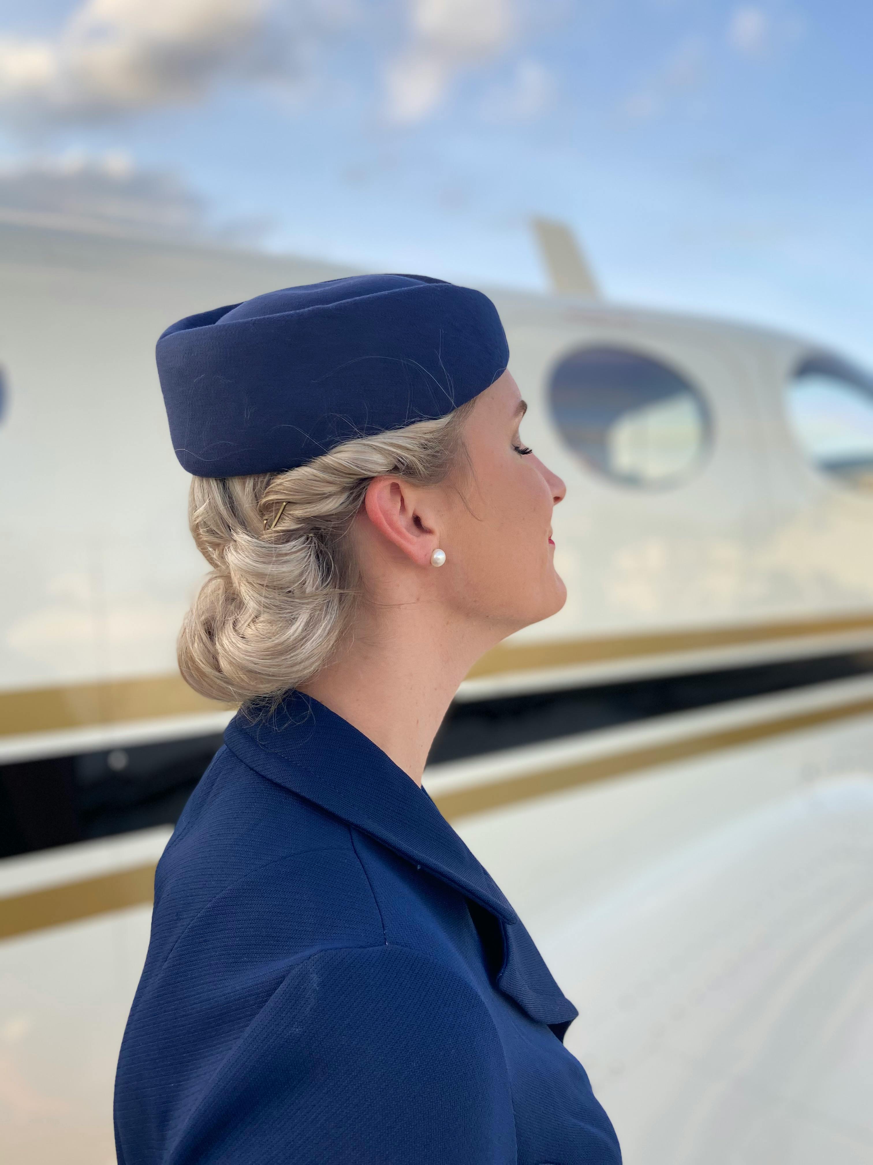 Une hôtesse de l'air heureuse à côté d'un avion | Source : Pexels