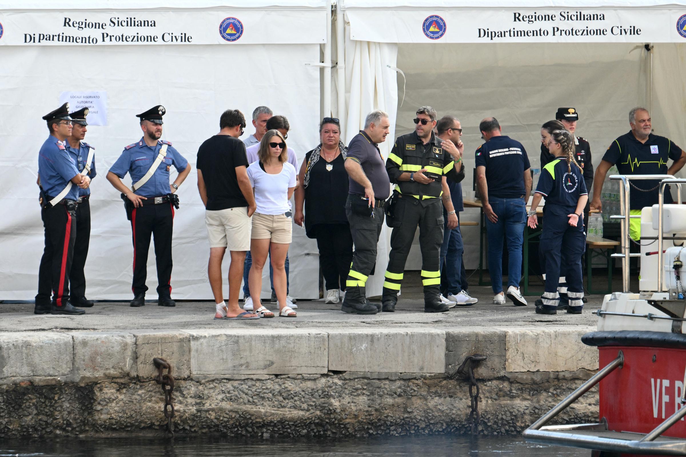 Des personnes se tiennent aux côtés des autorités locales et des sauveteurs sur la jetée de Porticello, près de Palerme, le 22 août 2024 | Source : Getty Images