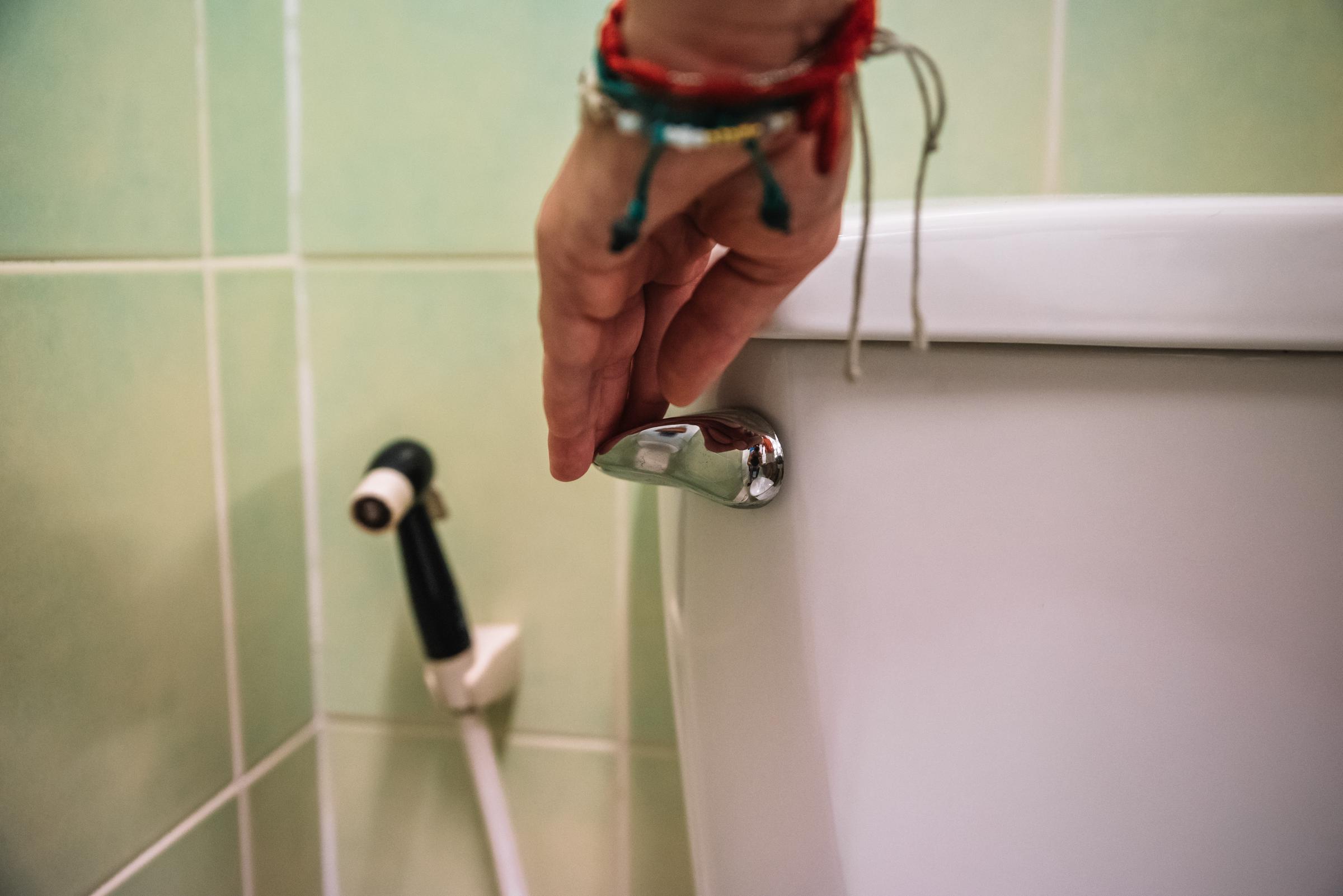 Gros plan d'une main tirant la chasse d'eau | Source : Getty Images