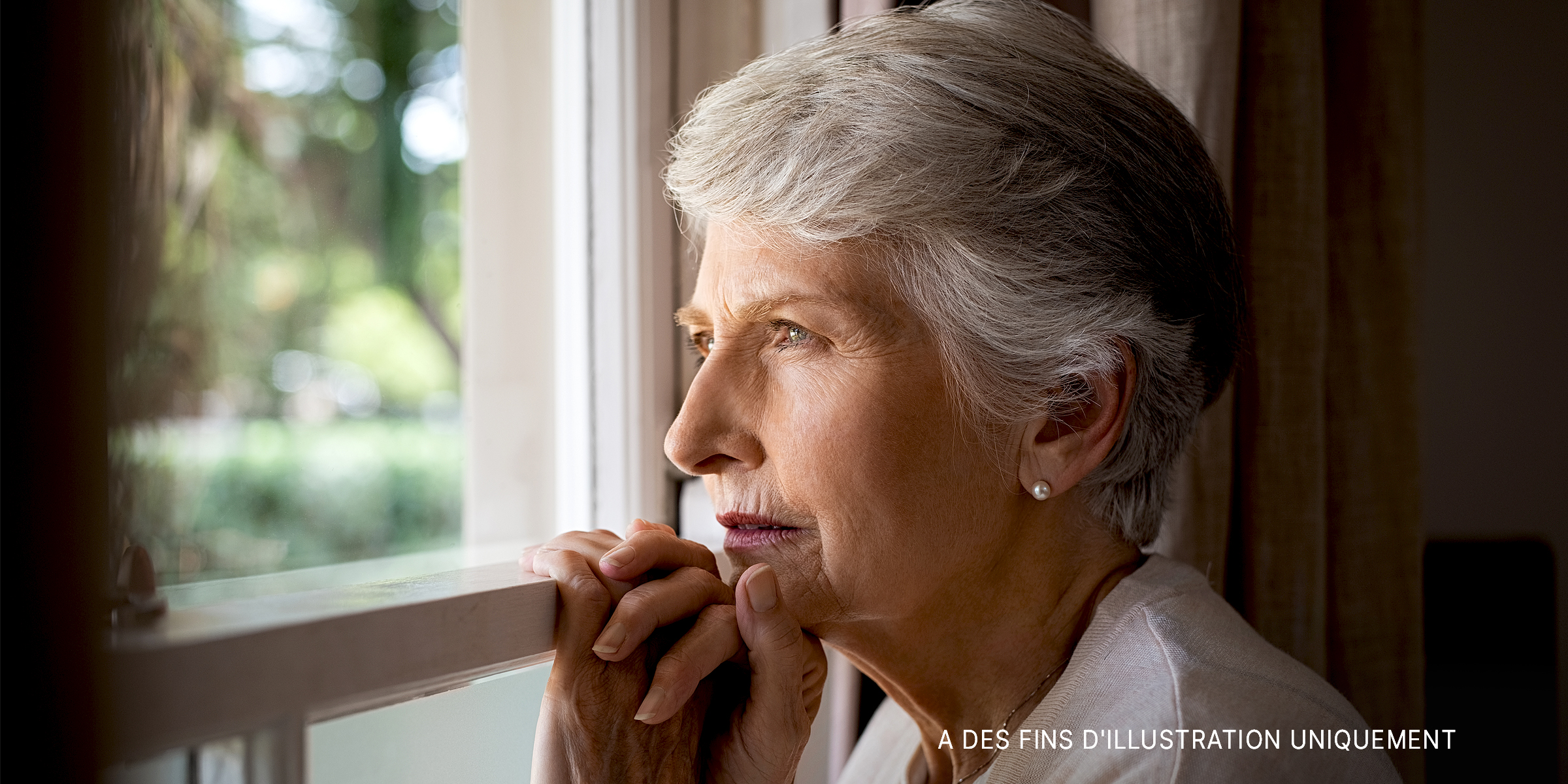 Femme âgée regardant par la fenêtre | Source : Getty Images