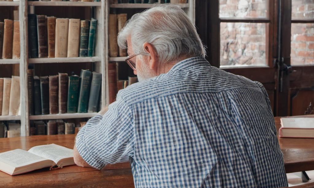 John assis seul dans son bureau, pensant à sa défunte femme | Source : Midjourney