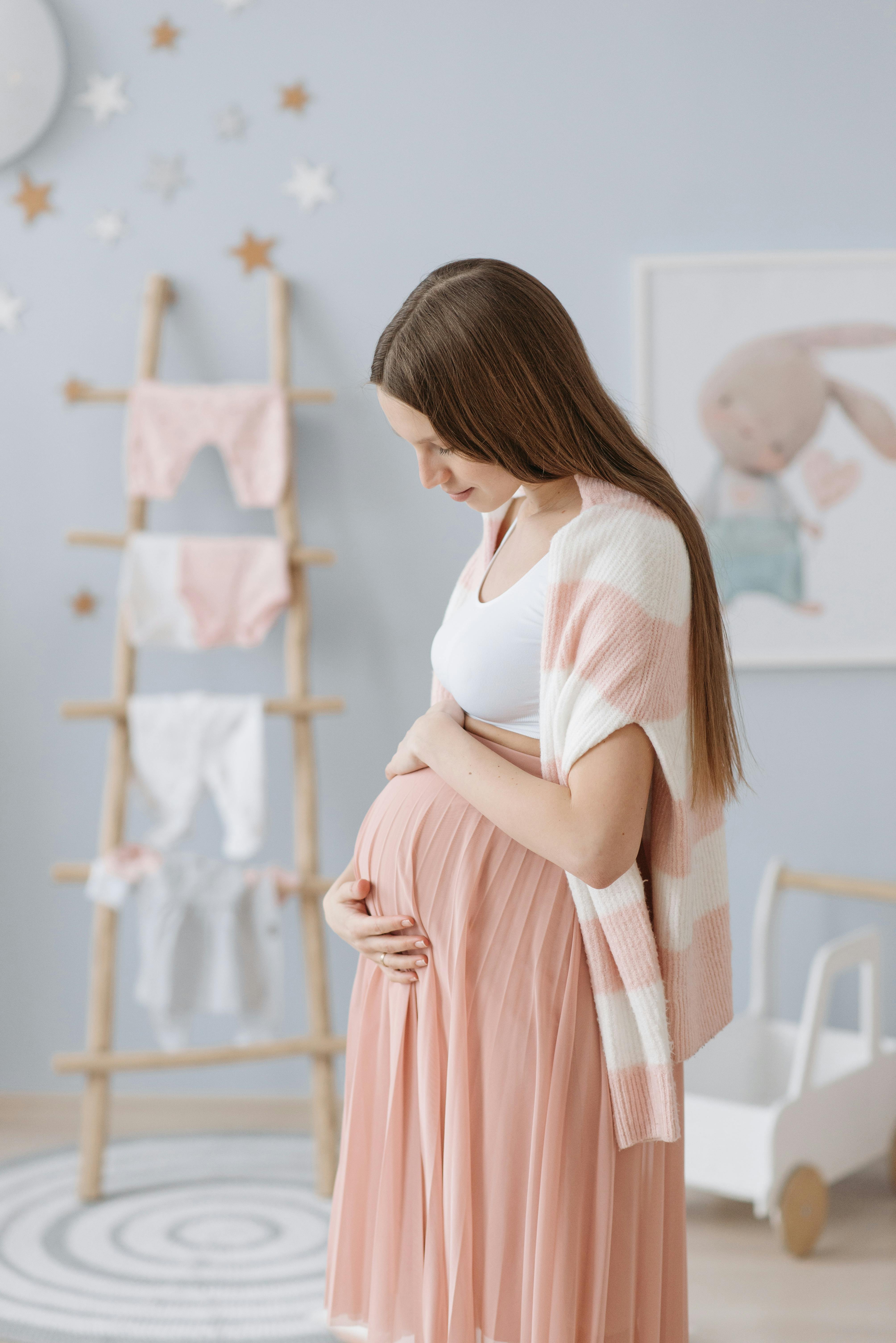 Une femme enceinte tenant son ventre dans la chambre de son futur bébé | Source : Pexels