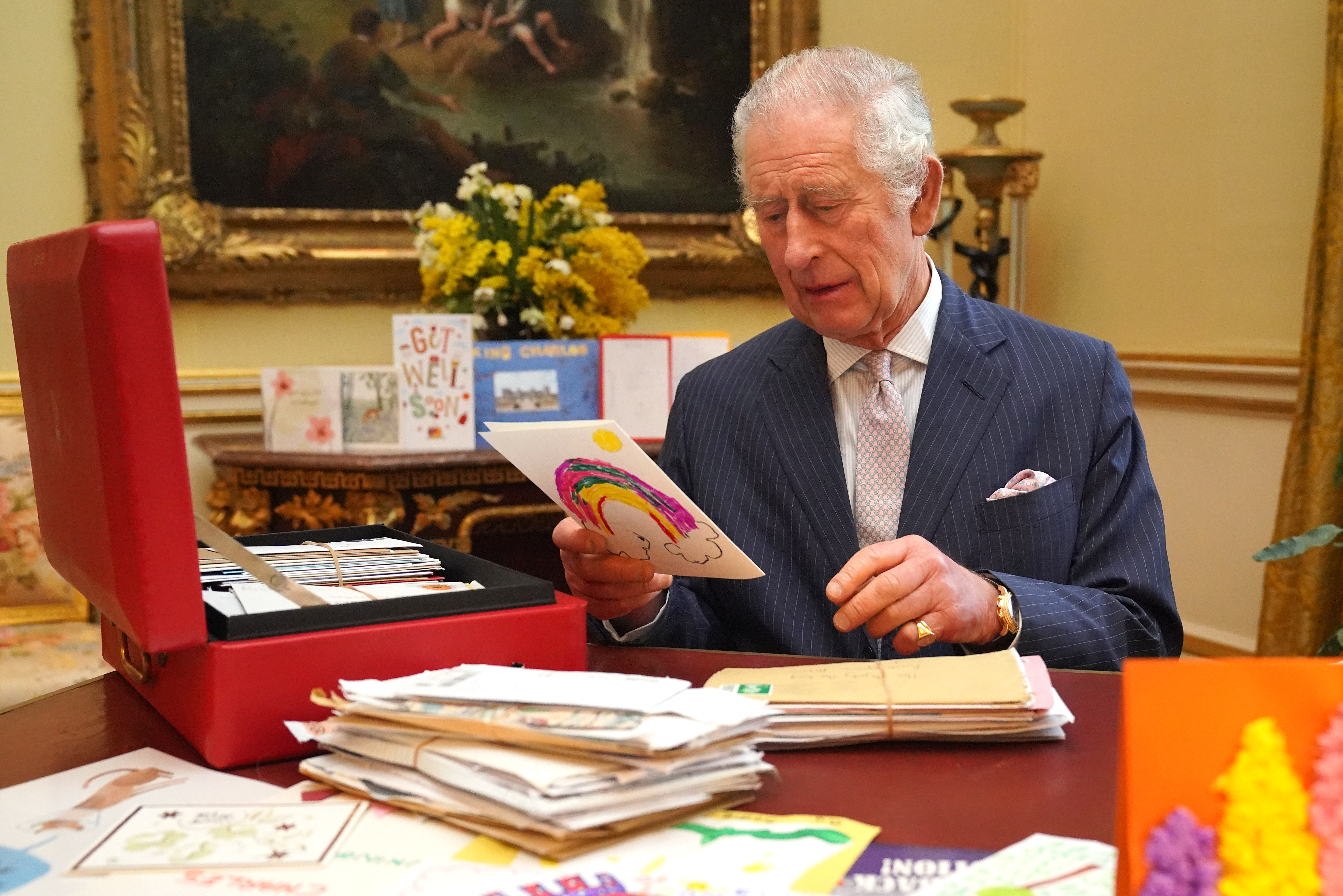 Le roi Charles lisant des cartes envoyées par des bienfaiteurs suite à son diagnostic de cancer, dans la salle du 18e siècle de la suite belge du palais de Buckingham, le 21 février 2024 à Londres, Angleterre | Source : Getty Images