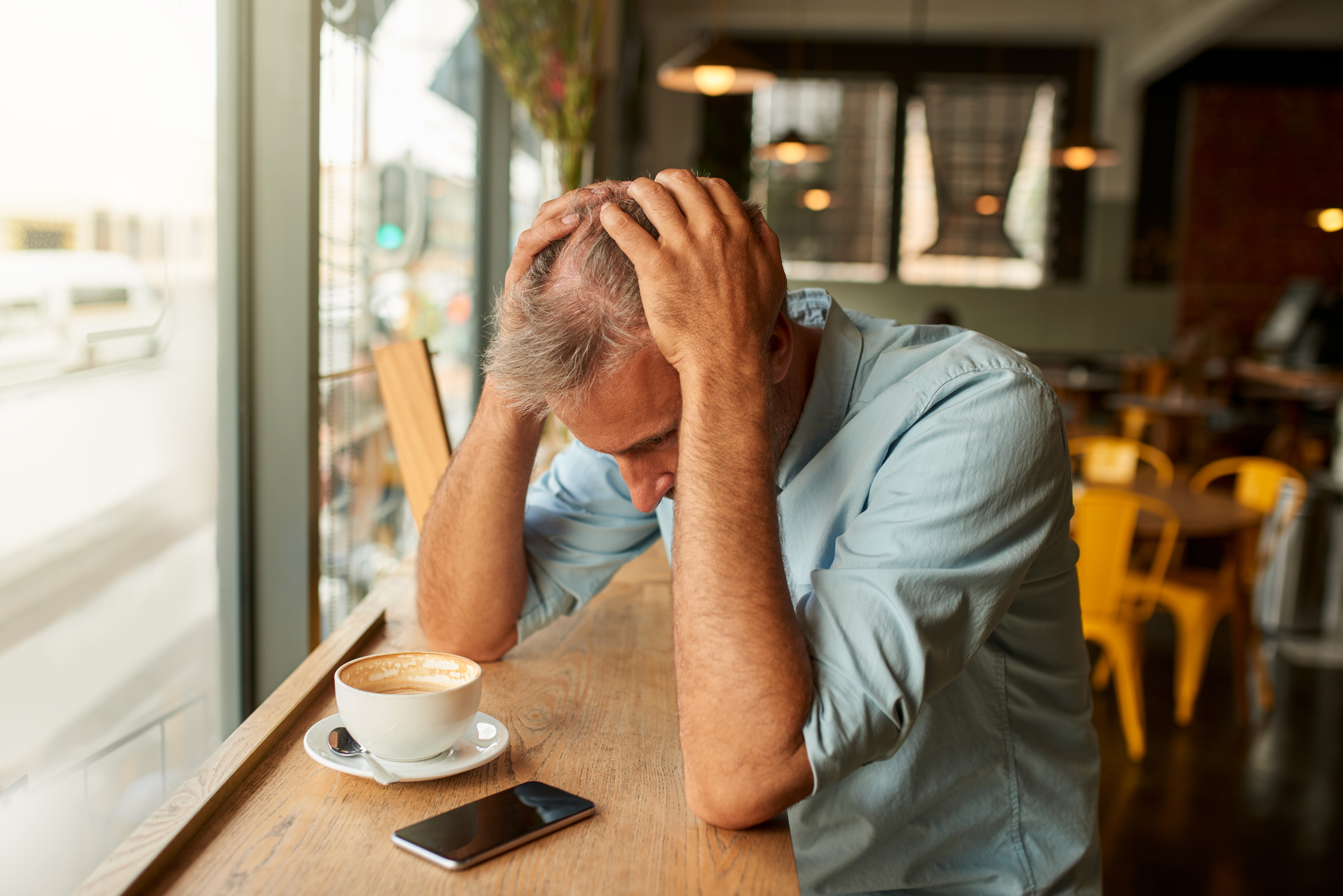 Un homme stressé regardant son téléphone portable dans un café | Source : Getty Images