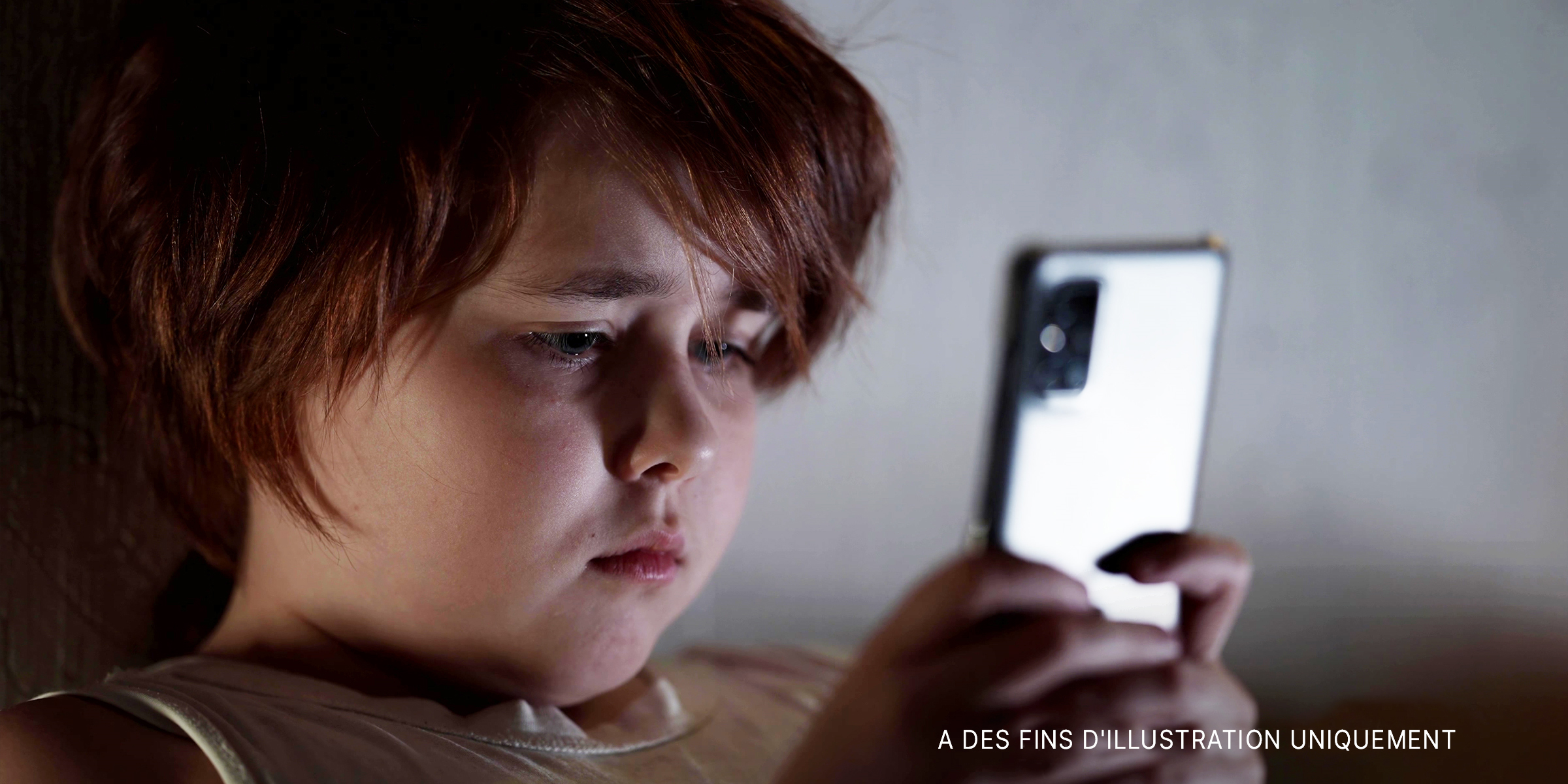 Un enfant regardant un téléphone portable│Source : Shutterstock