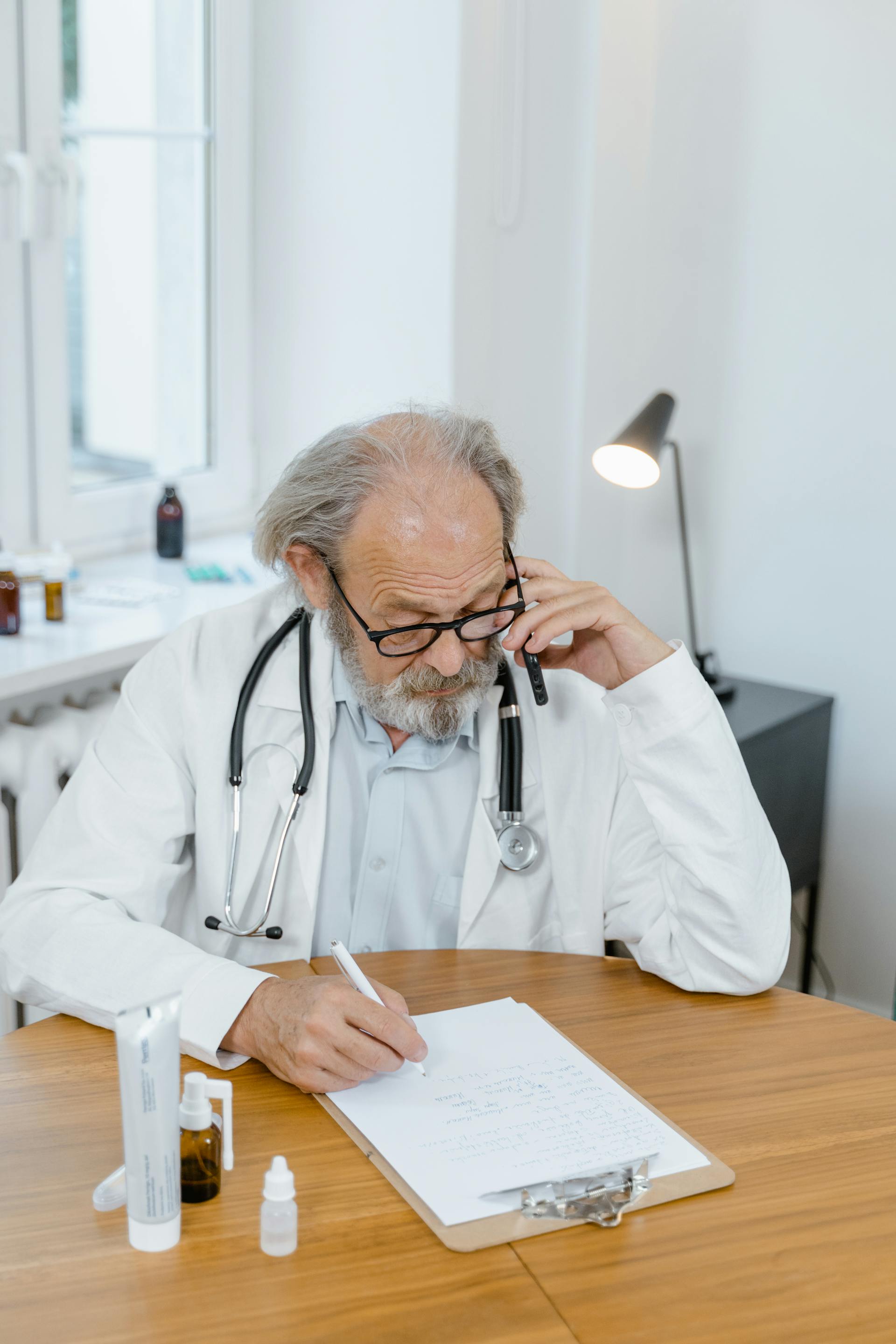 Un médecin au téléphone et en train d'écrire | Source : Pexels