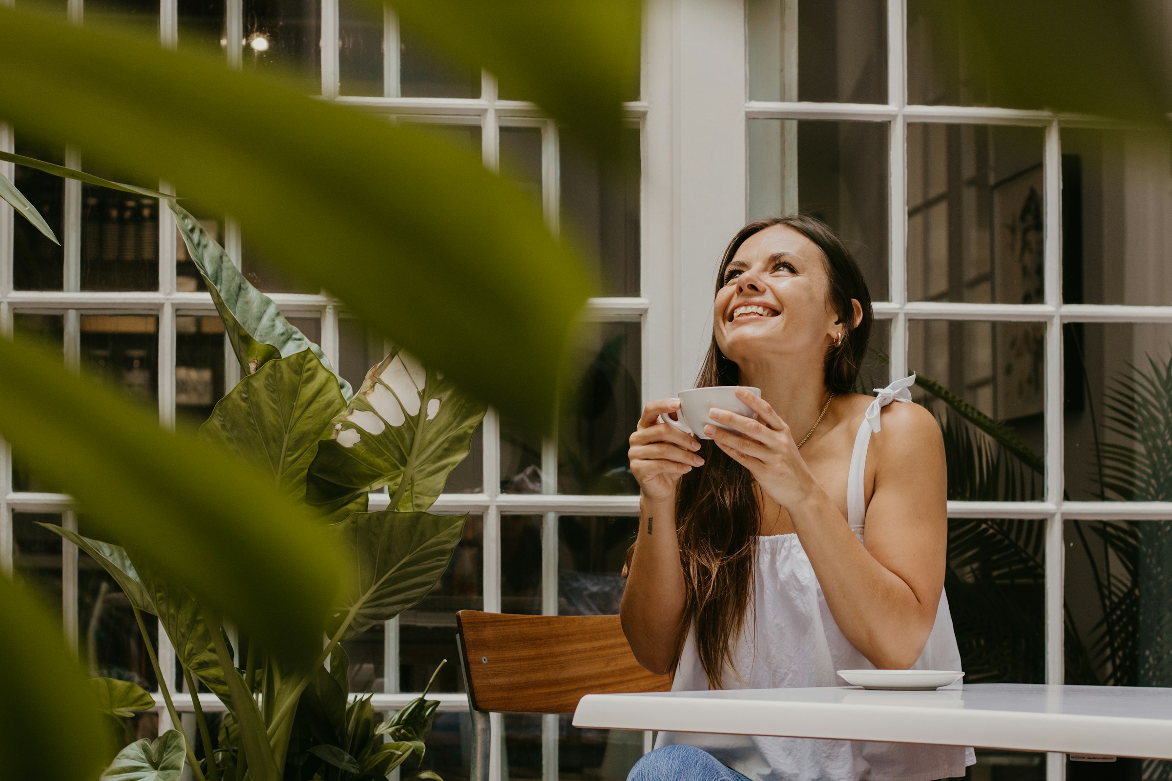 Une jeune femme sourit en tenant une tasse de café | Source : Unsplash