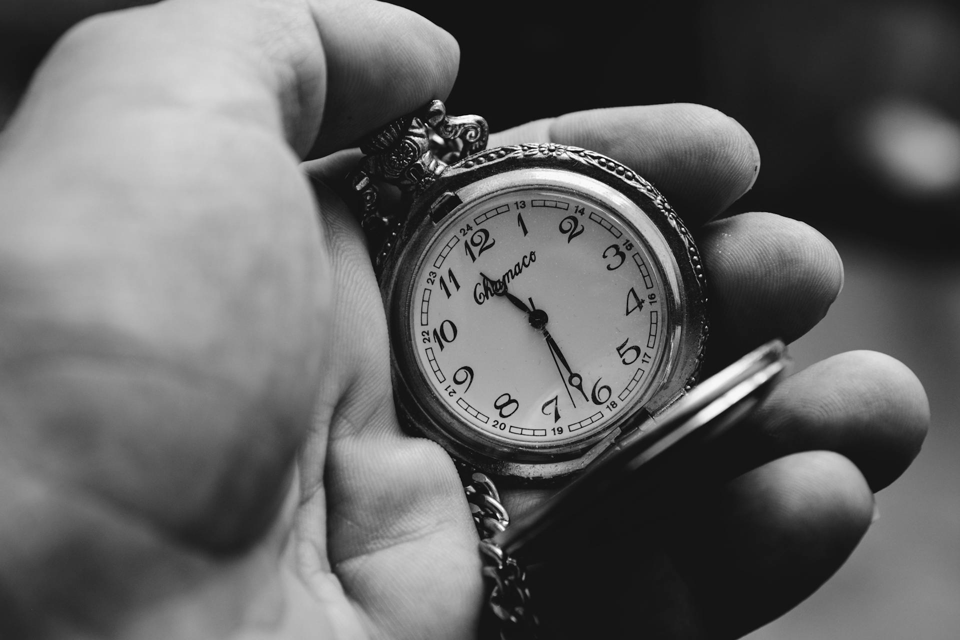 Photo en niveaux de gris d'une personne tenant une montre à gousset vintage | Source : Pexels