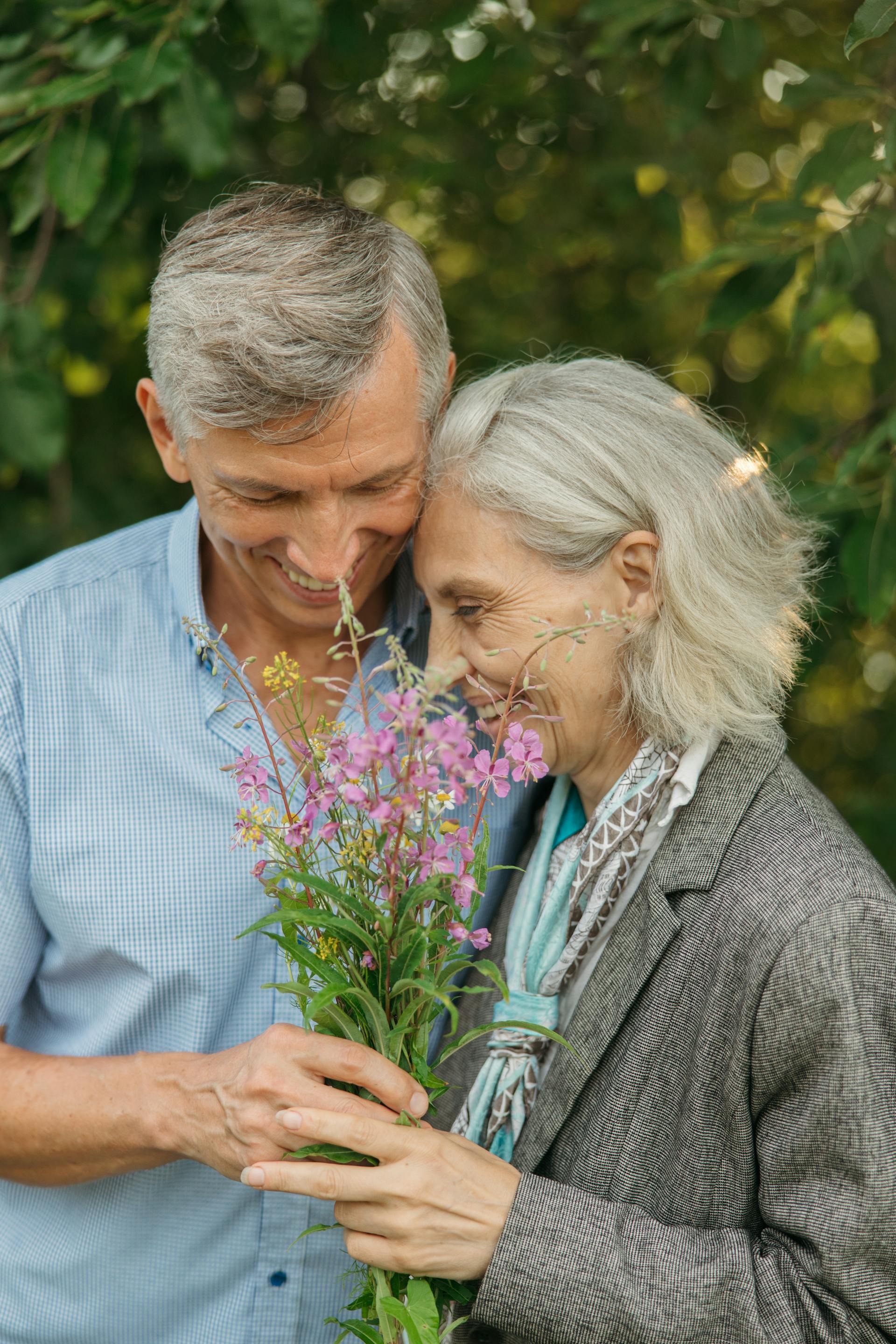 Un gros plan sur un couple de personnes âgées tenant des fleurs | Source : Pexels
