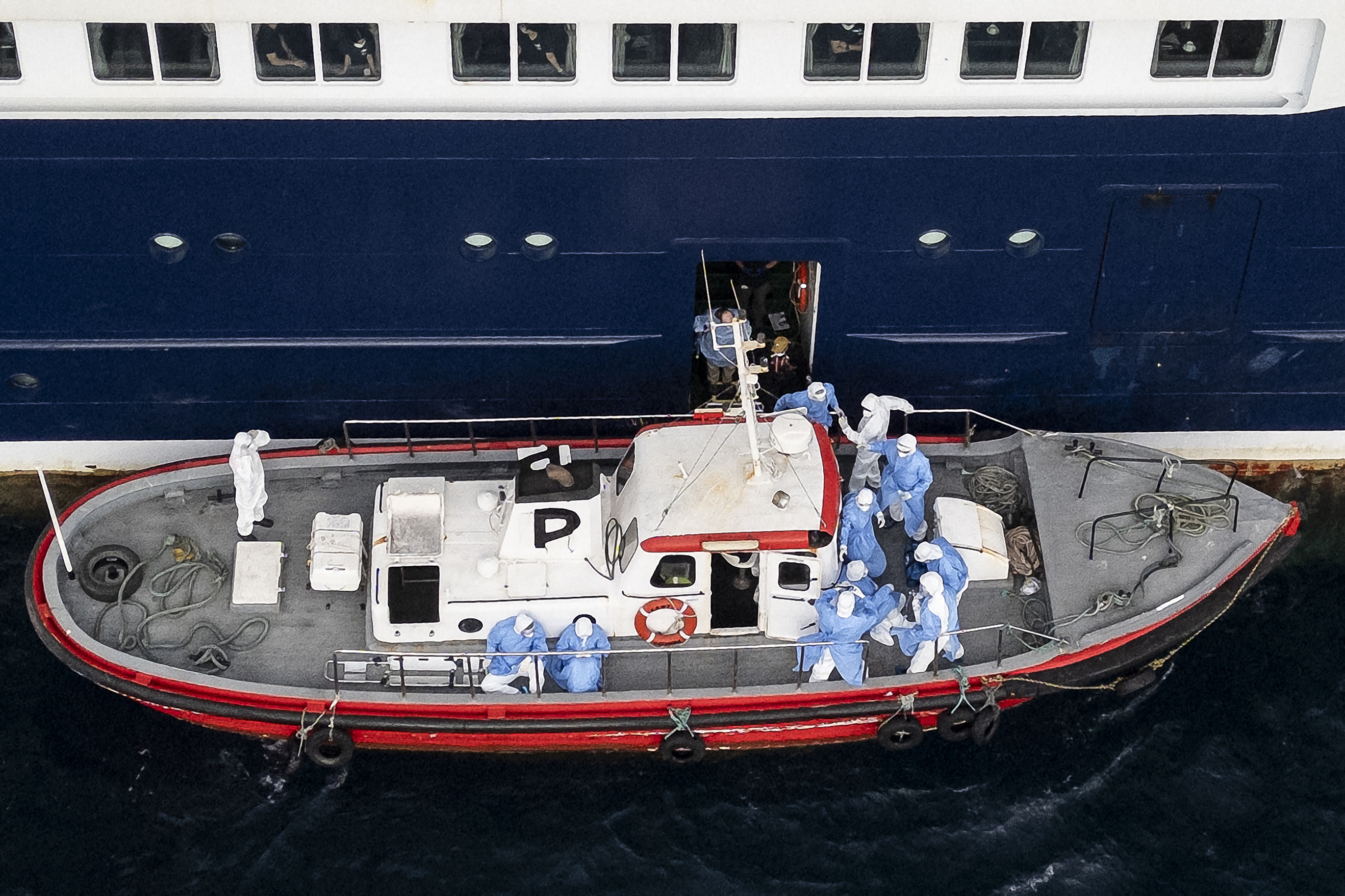 Cette vue aérienne montre des membres du personnel de santé aidant des patients à monter à bord d'un bateau depuis le navire de croisière MV Hondius, alors que celui-ci était à quai dans le port de Praia, la capitale du Cap-Vert, le 6 mai 2026 I Source : Getty Images