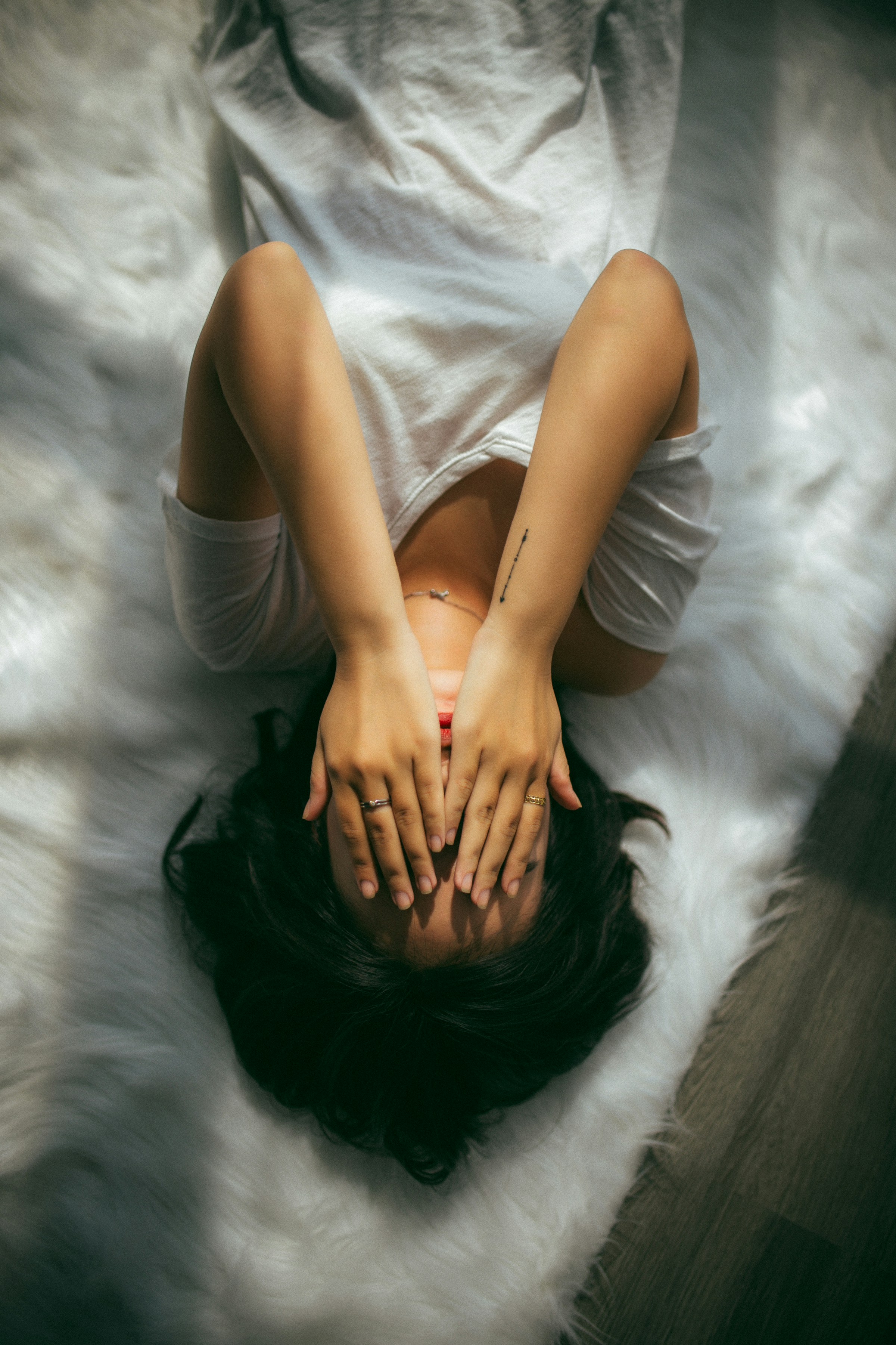 Une femme allongée sur son lit cachant son visage | Souce : Unsplash