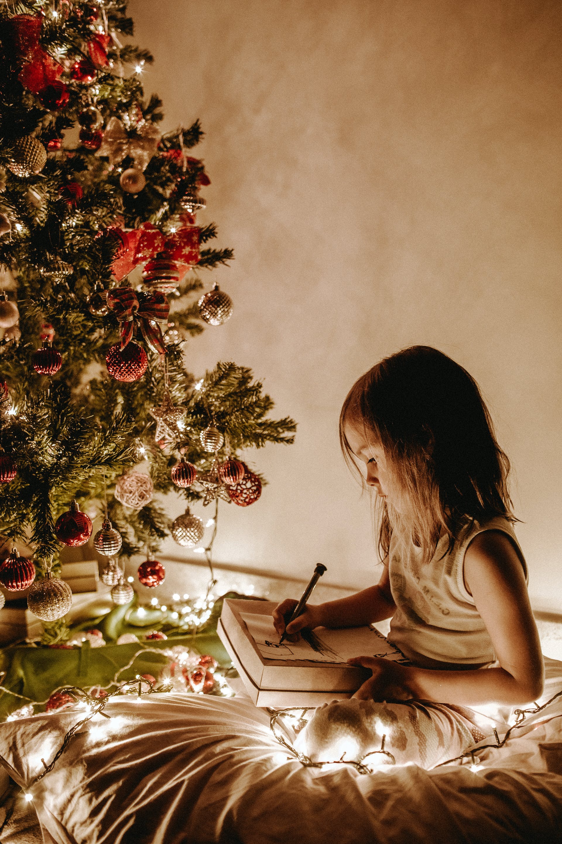 Une petite fille assise près d'un sapin de Noël | Source : Pexels