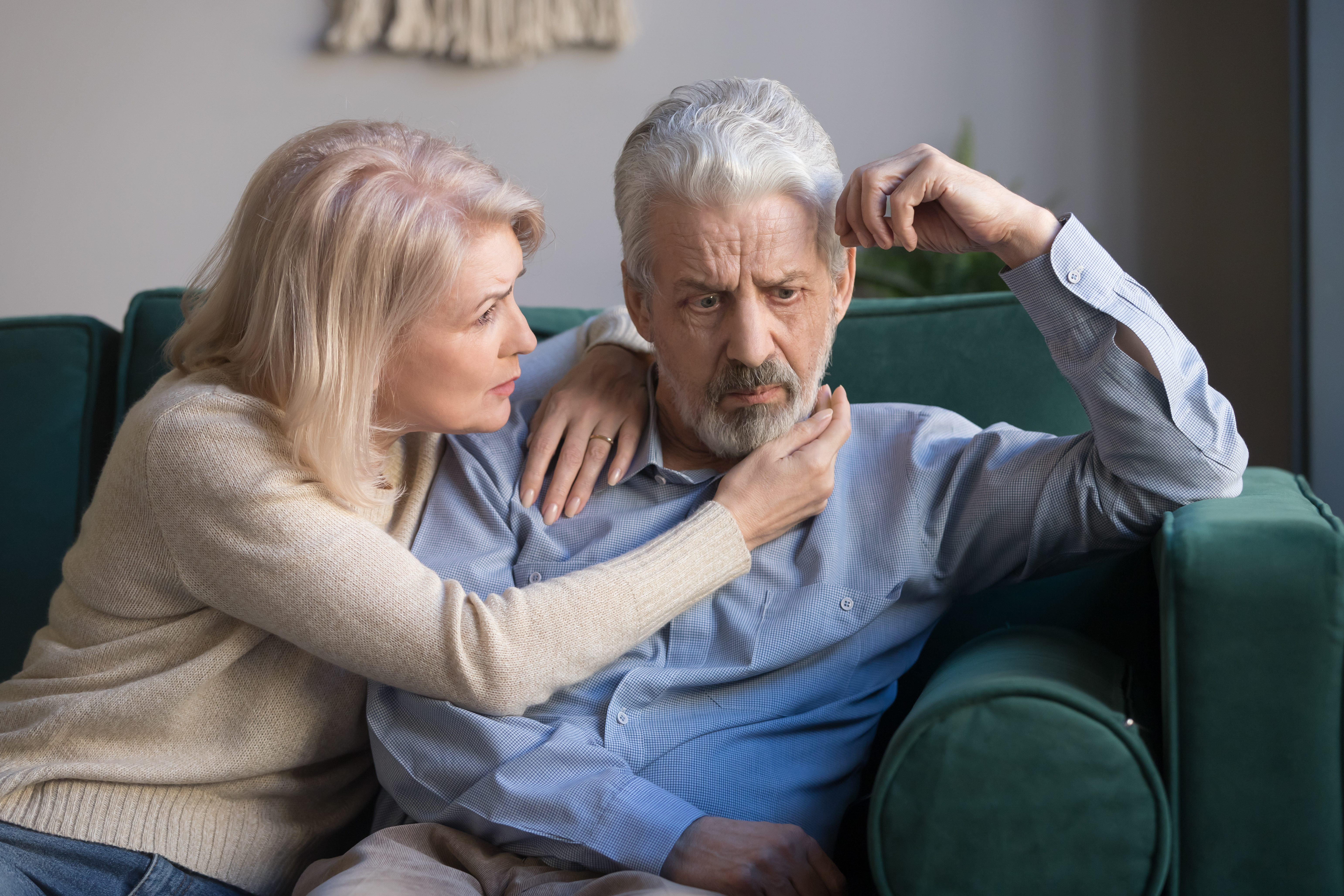 Une femme d'âge moyen réconforte son mari aux cheveux gris bouleversés | Source : Shutterstock