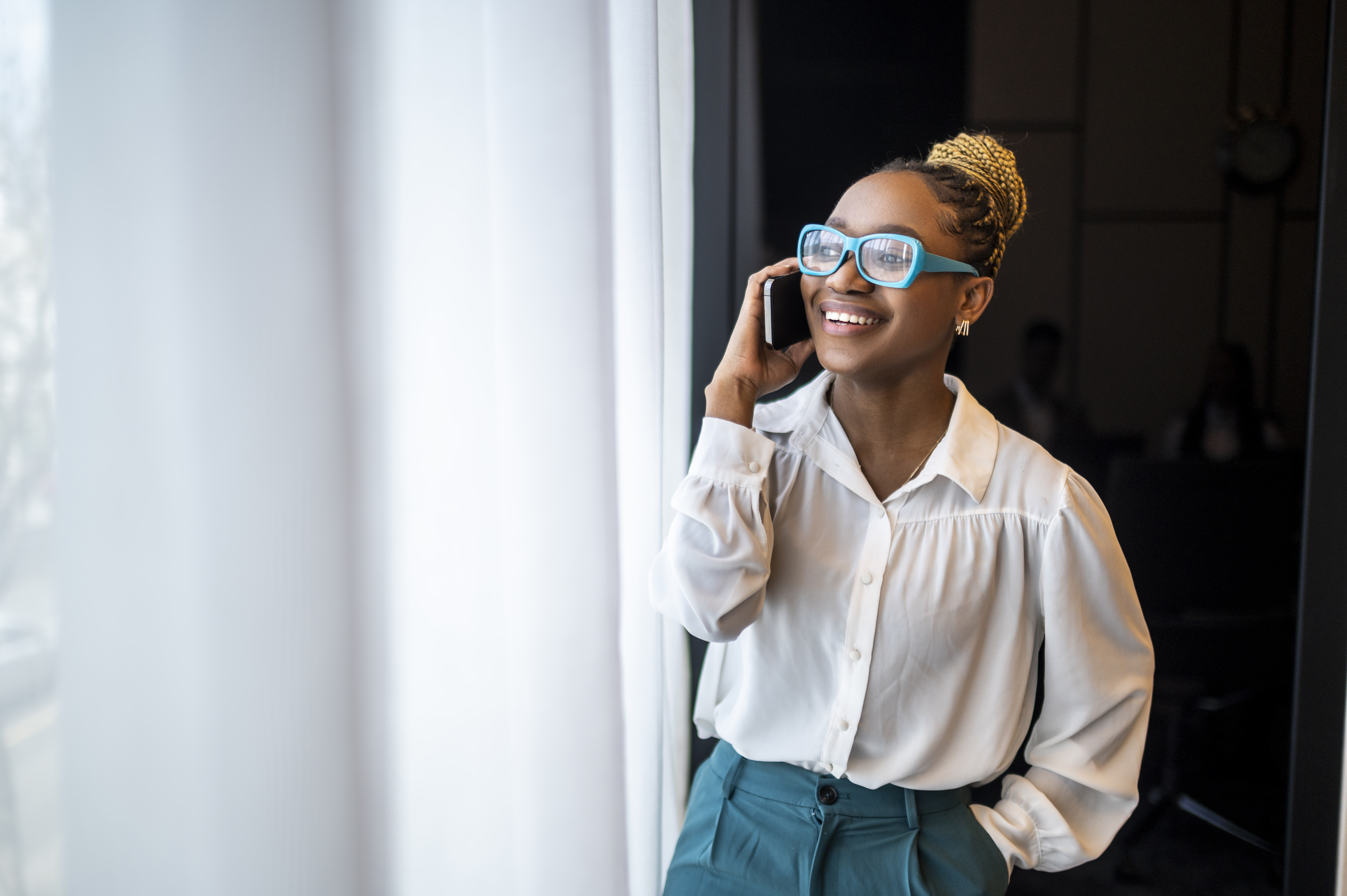 Portrait d'une entrepreneuse noire souriante qui parle au téléphone | Source : Getty Images
