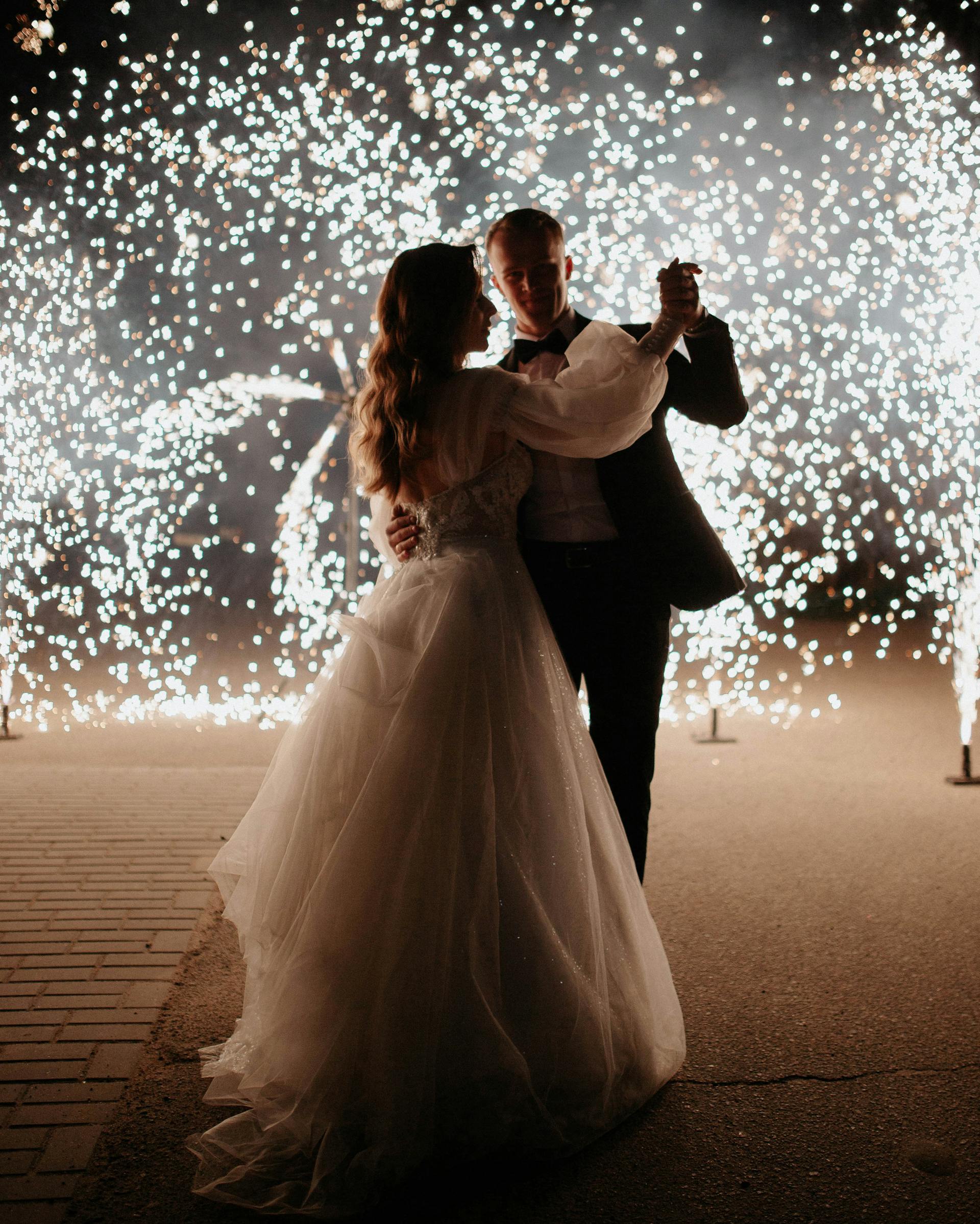Une mariée et un marié dansant avec des feux d'artifice dans l'obscurité | Source : Pexels