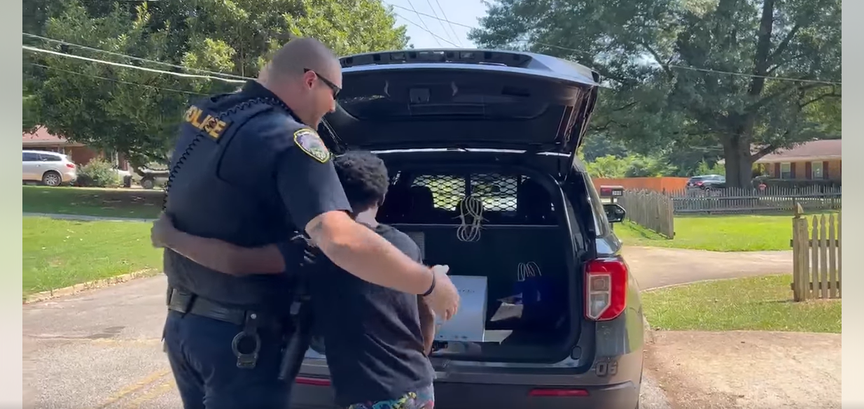 L'officier Colleran embrasse un garçon après l'avoir emmené dans le coffre de sa voiture pour lui montrer quelque chose, après que les habitants du quartier ont appelé la police pour l'enfant, le 24 juillet 2023 | Source : Facebook/City of Hapeville Police