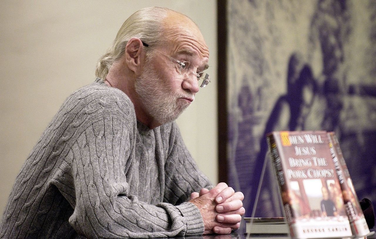 George Carlin parle de son nouveau livre "Quand Jésus apportera-t-il les côtelettes de porc?" lors d'une séance de dédicace chez Barnes and Noble. | Source : Getty Images