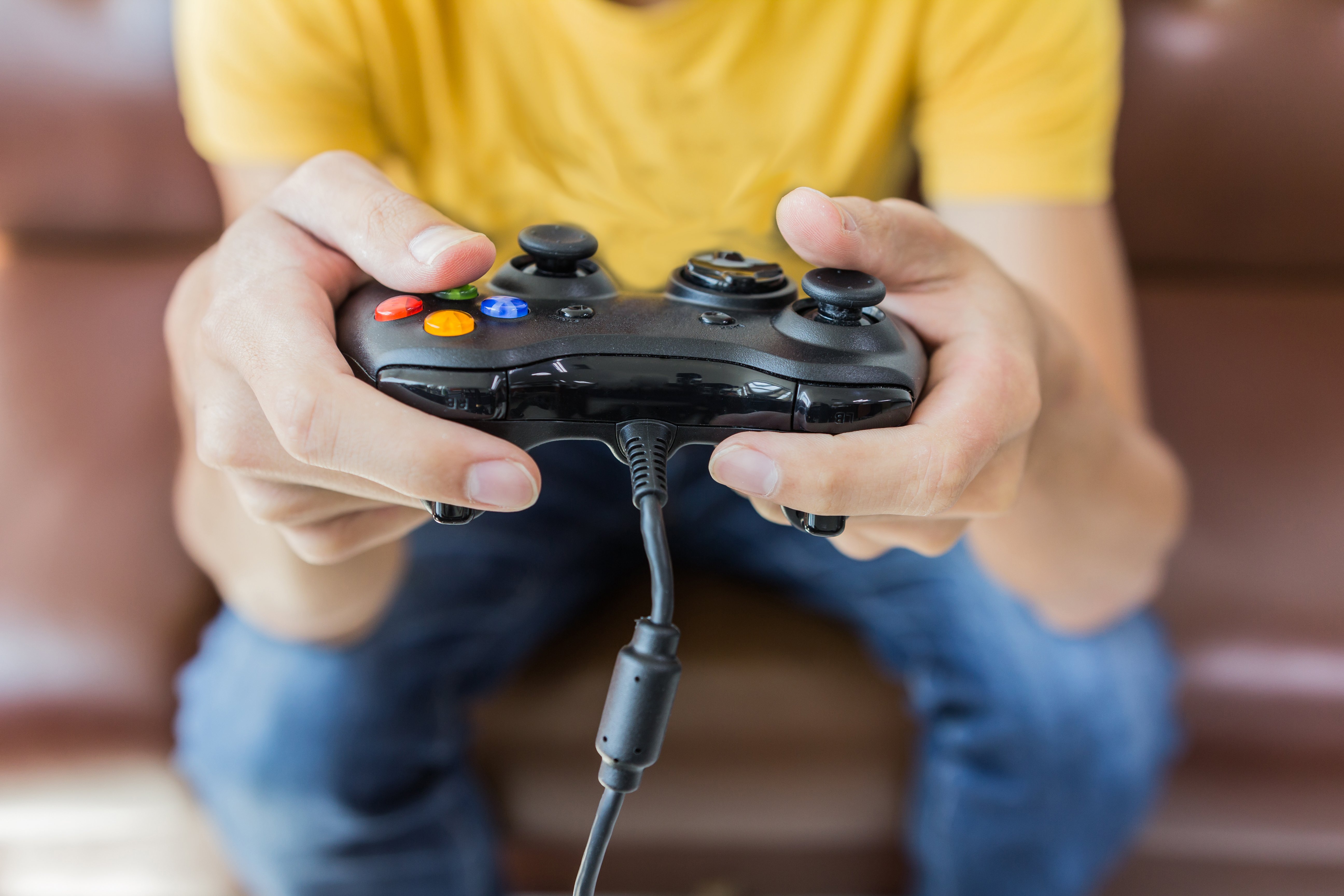 Un homme tenant une manette de jeu jouant à des jeux vidéo | Photo : Shutterstock