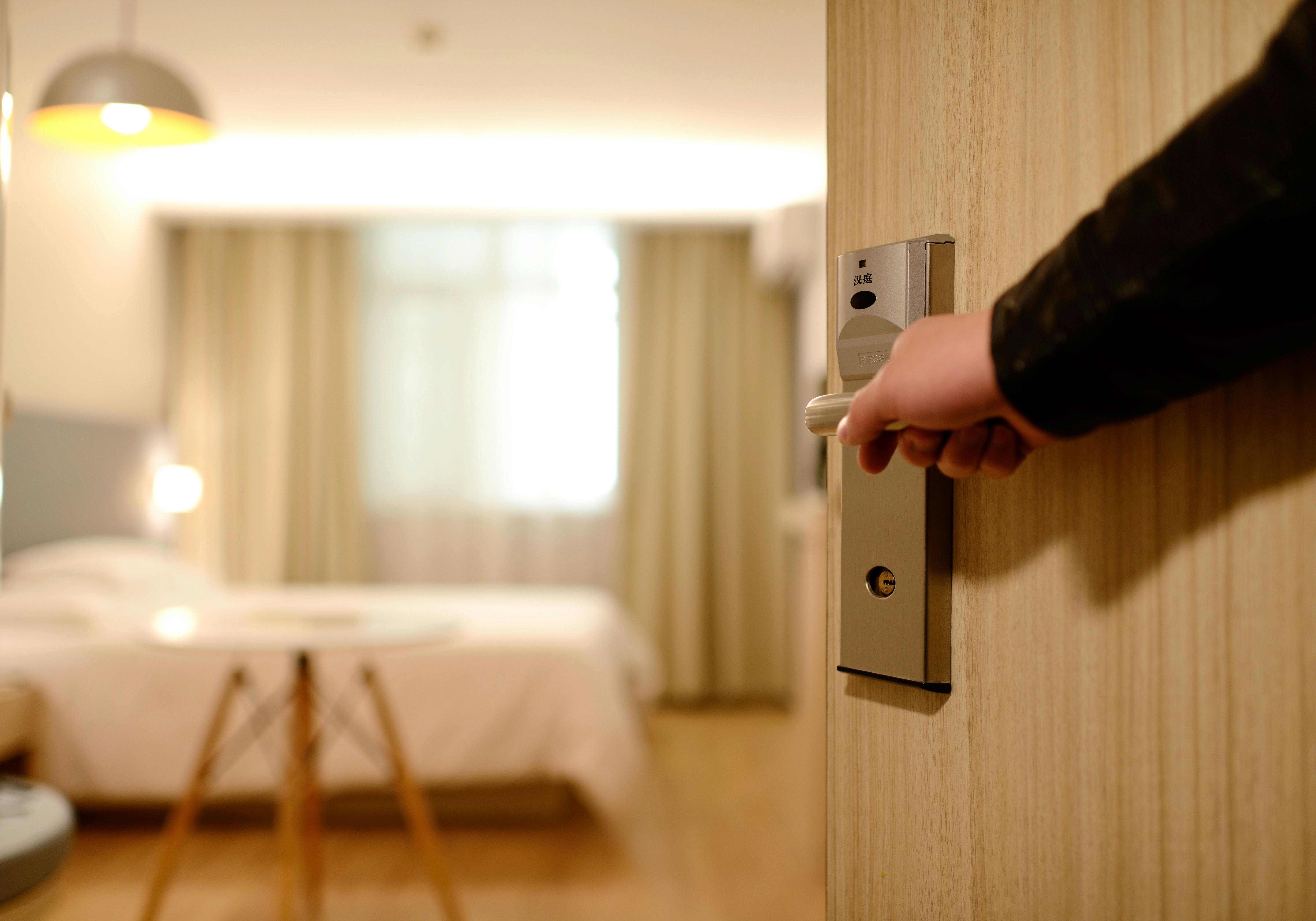 Une personne tenant la porte d'une chambre d'hôtel ouverte | Source : Pexels