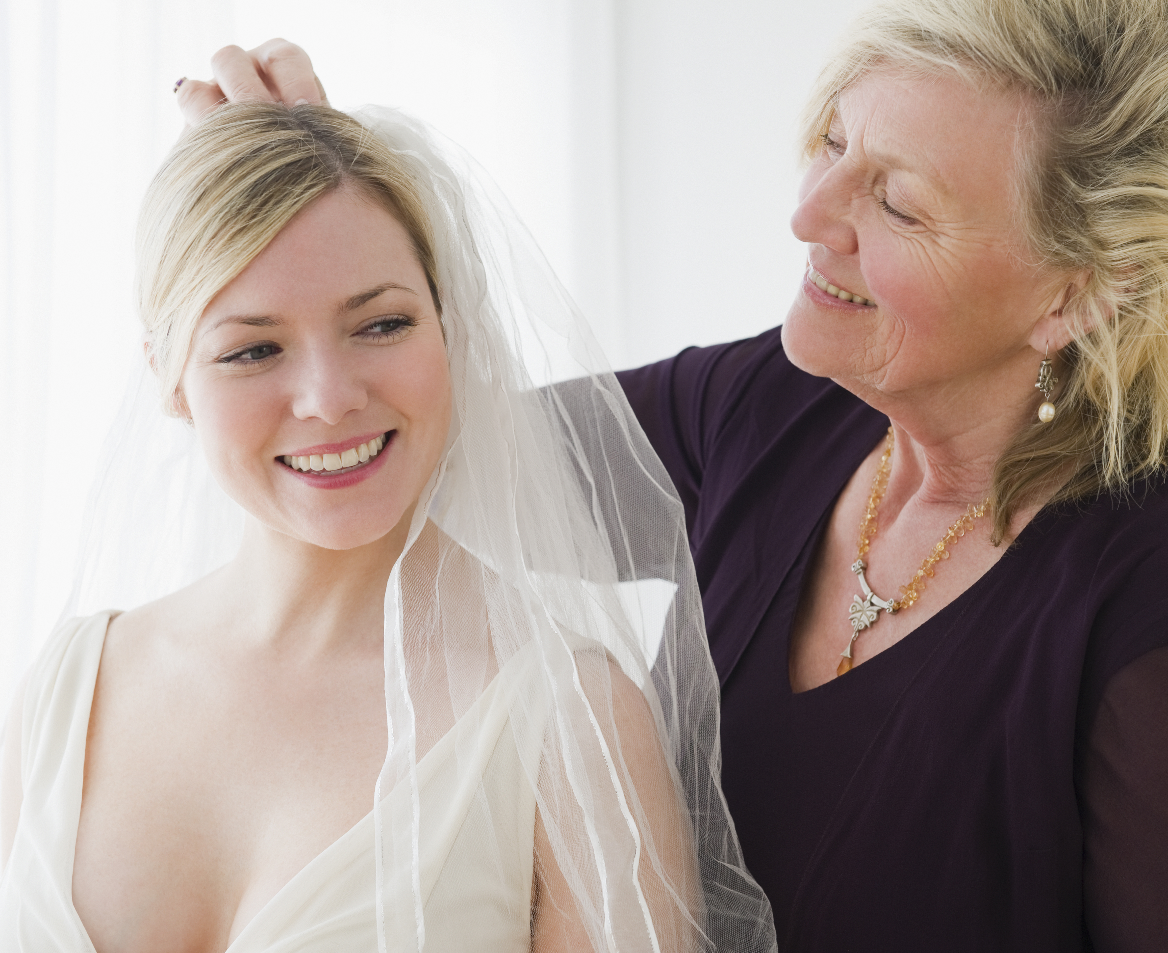 Une femme plus âgée aide une femme plus jeune à essayer une robe de mariée | Source : Getty Images