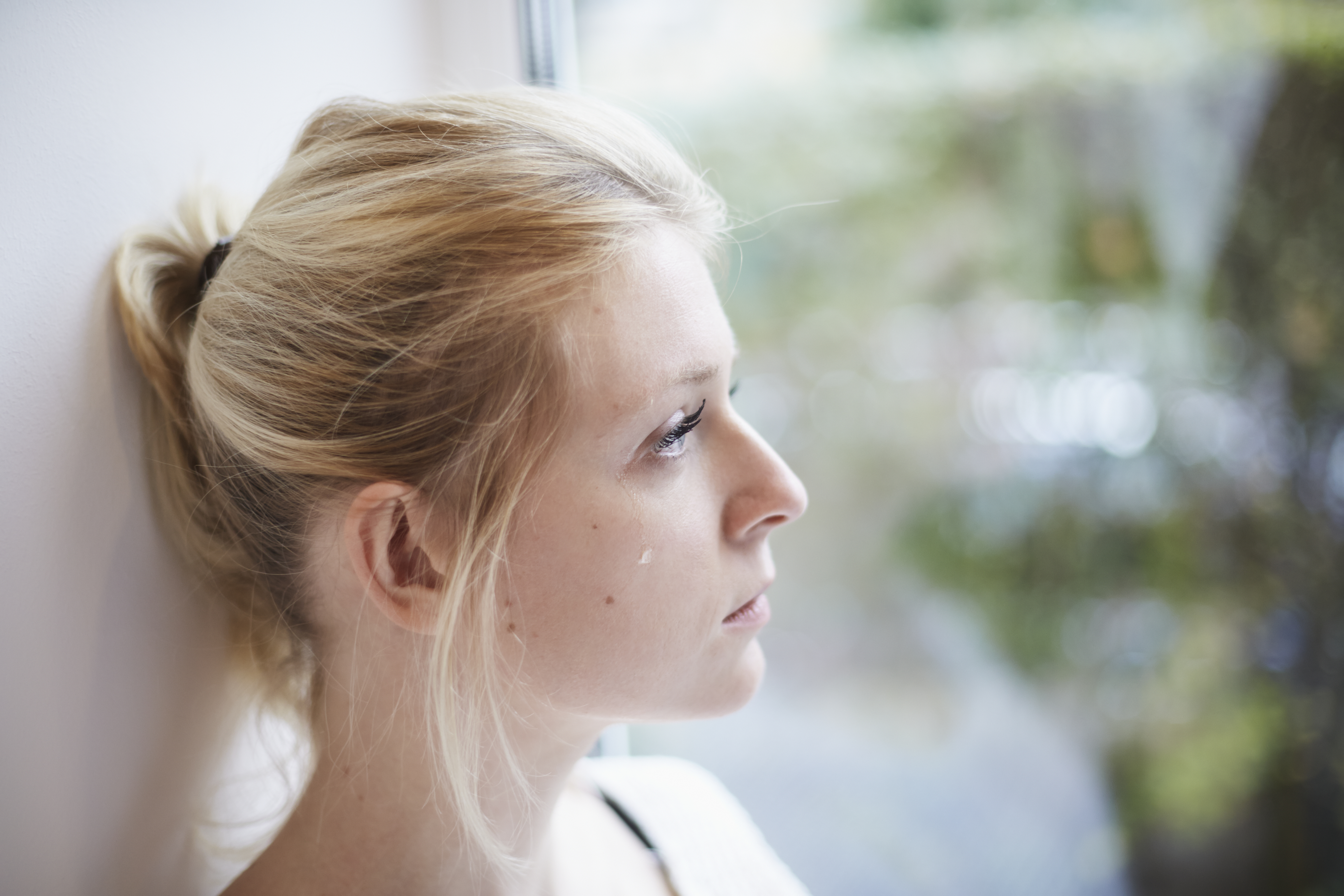 Jeune femme pleurant à la fenêtre | Source : Getty Images
