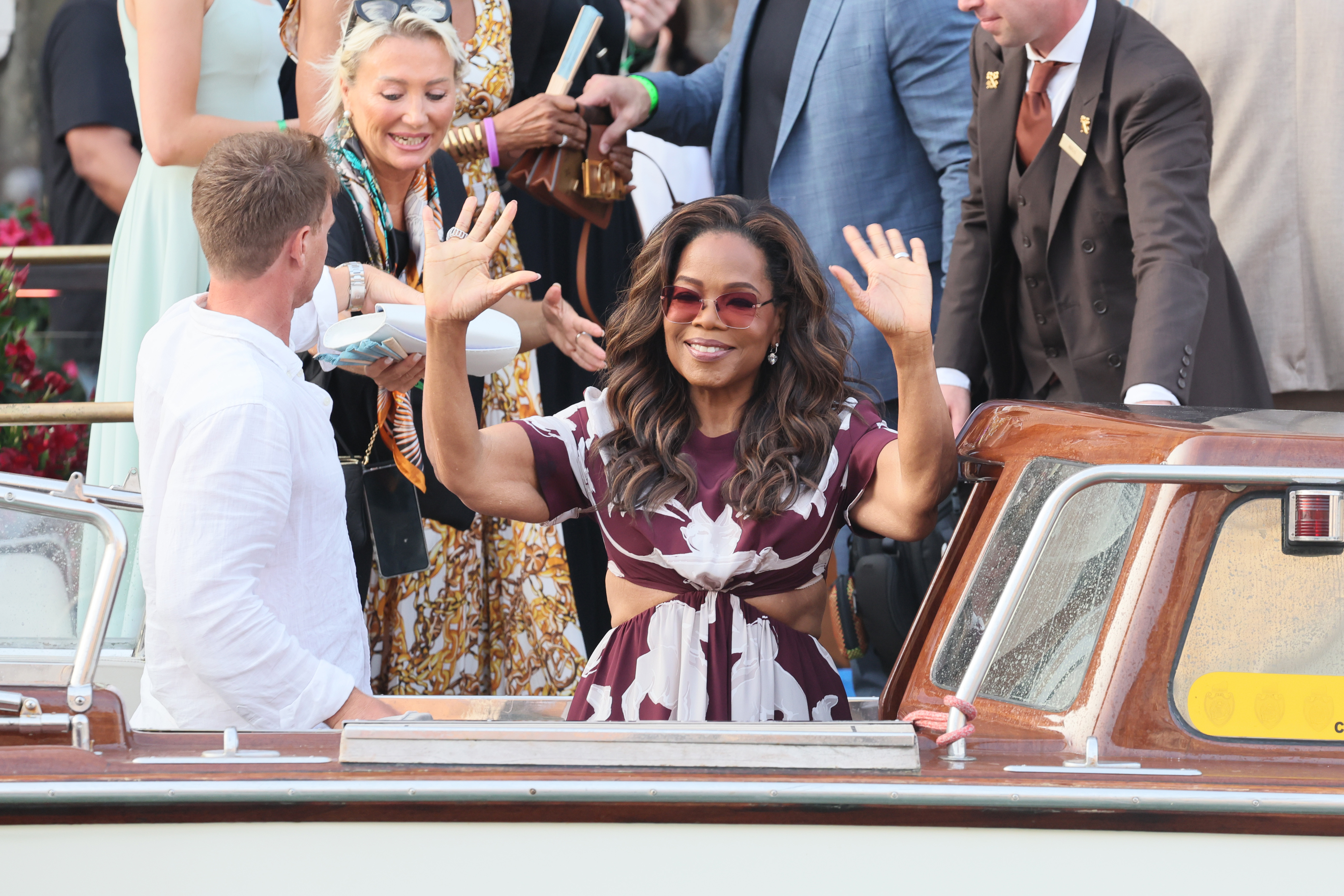 Oprah Winfrey sourit et salue la foule alors qu'elle arrive devant Jeff Bezos et Lauren Sanchez pour leur mariage à Venise, en Italie, le 26 juin 2025. La peau flasque autour de ses bras, qui fait beaucoup parler les médias, est visible lorsqu'elle lève les mains en l'air.