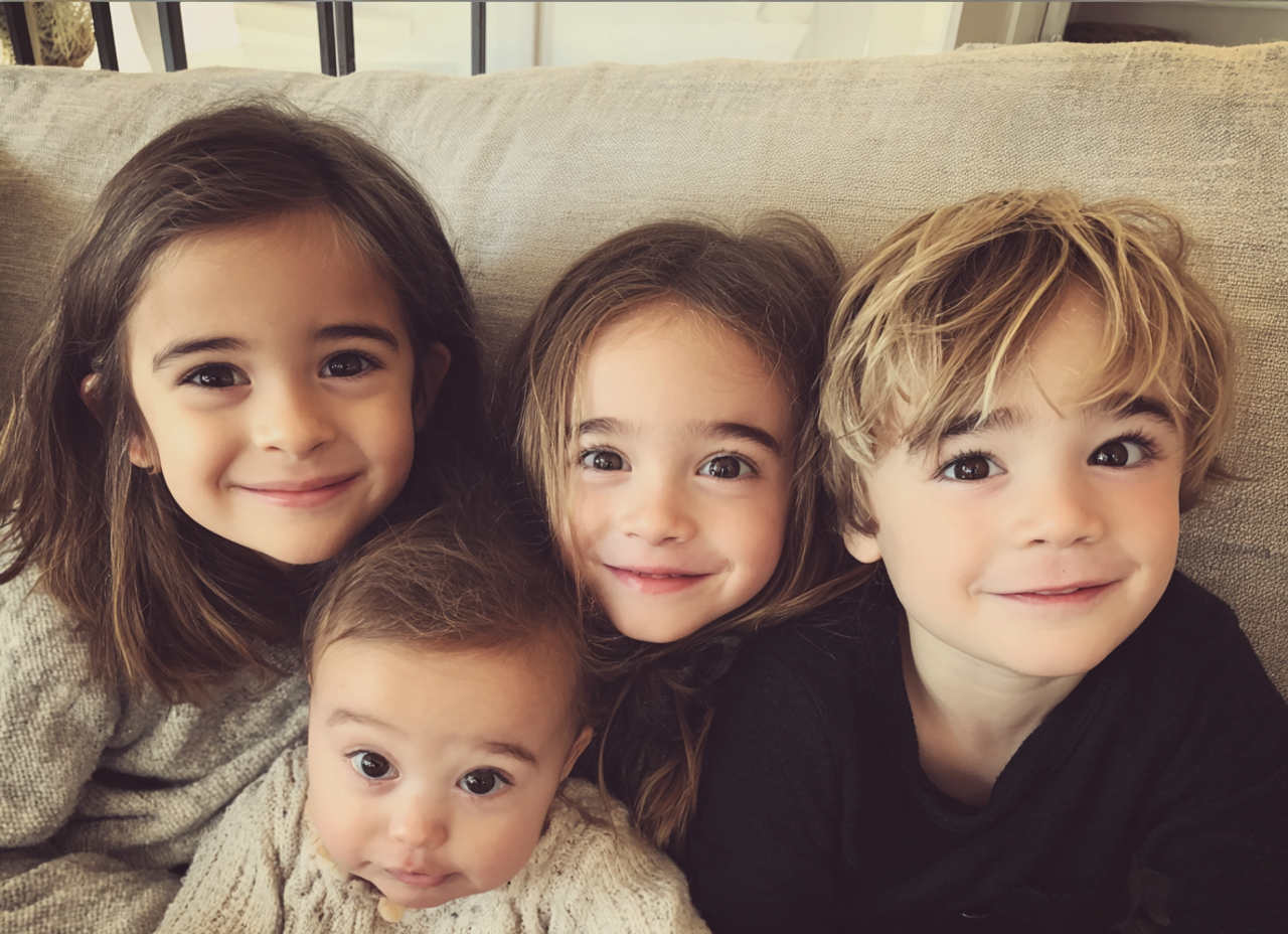 Quatre jeunes enfants assis sur un canapé | Source : Midjourney