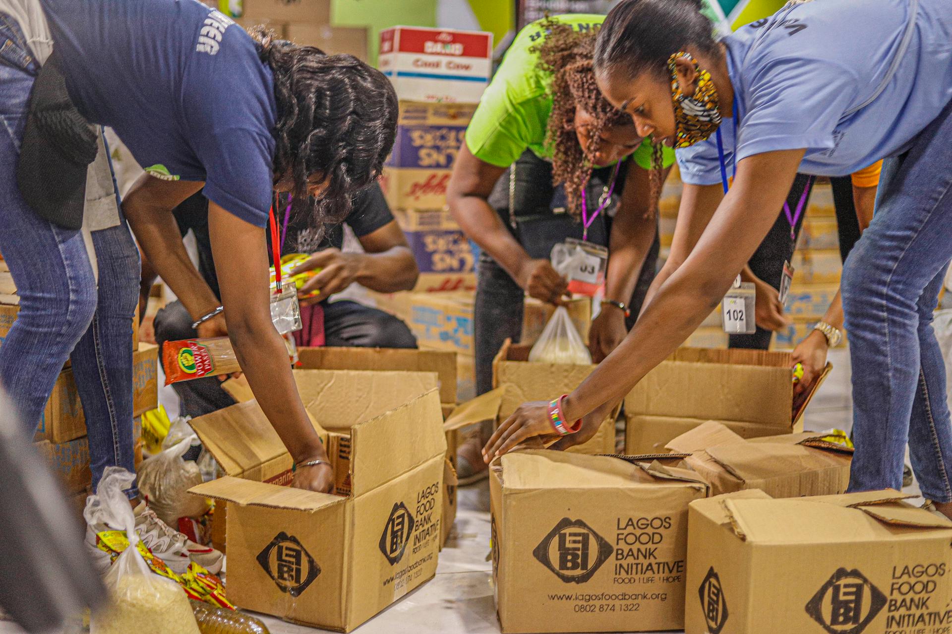 Des bénévoles d'une banque alimentaire emballent des articles dans des boîtes en carton | Source : Pexels