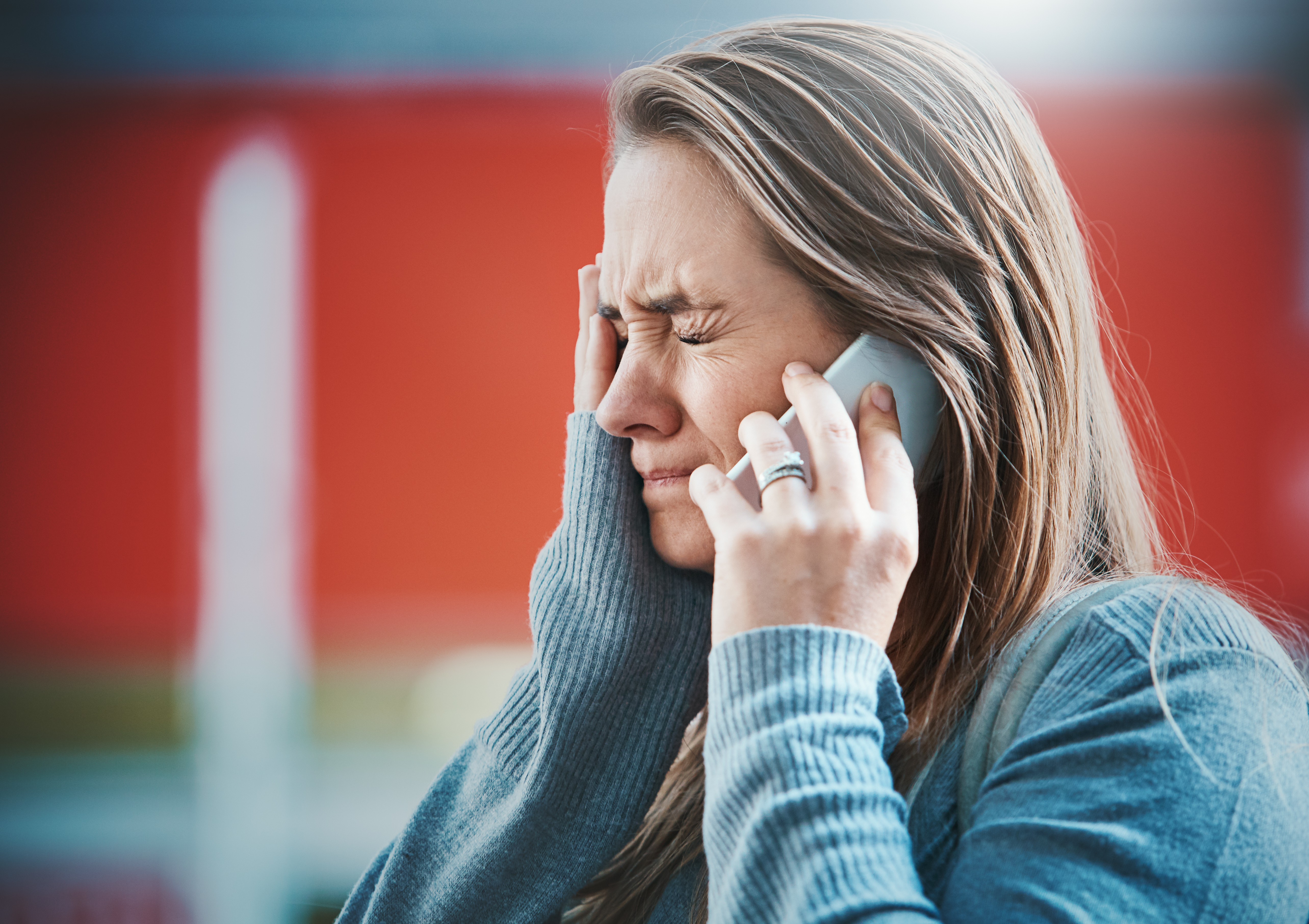 Jeune femme retenant ses larmes au téléphone | Source : Getty Images