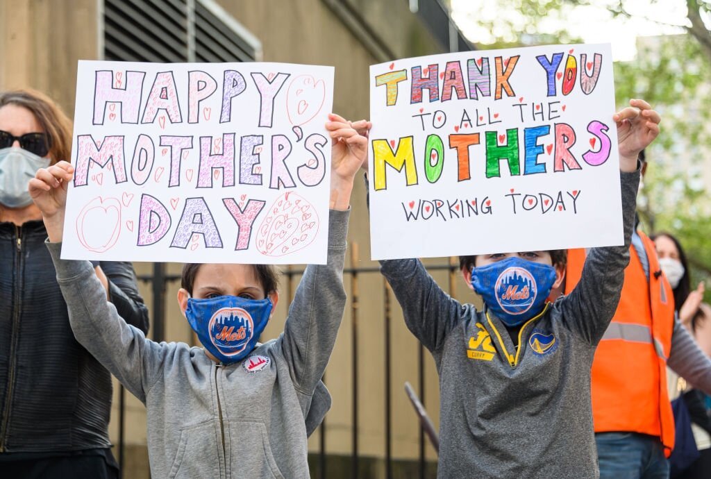 NEW YORK - 10 MAI : Des enfants brandissent des pancartes de fête des mères devant le centre de santé NYU Langone pour exprimer leur gratitude au personnel médical et aux travailleurs essentiels qui travaillent en première ligne sur la pandémie de coronavirus le 10 mai 2020 à New York. | Photo : Getty Images