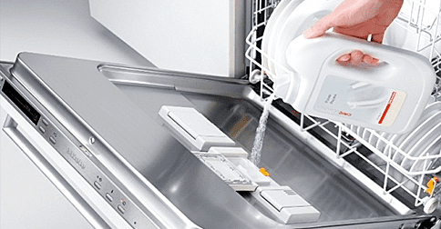 Une main qui verse du détergent dans le Lave-vaisselle | Photo : Shutterstock